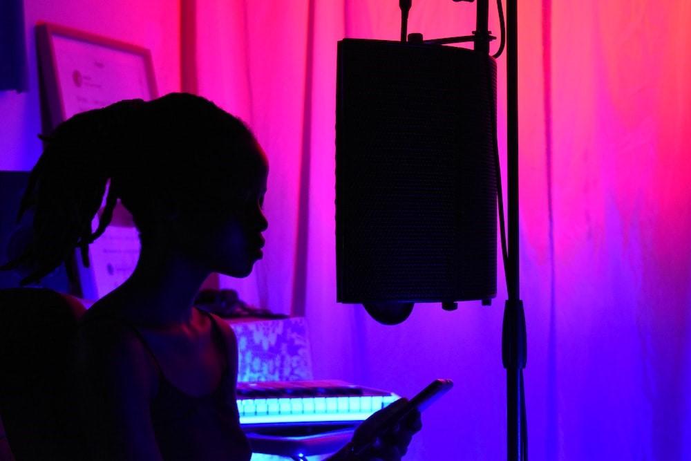 A girl recording music with the help of music speakers to create music.