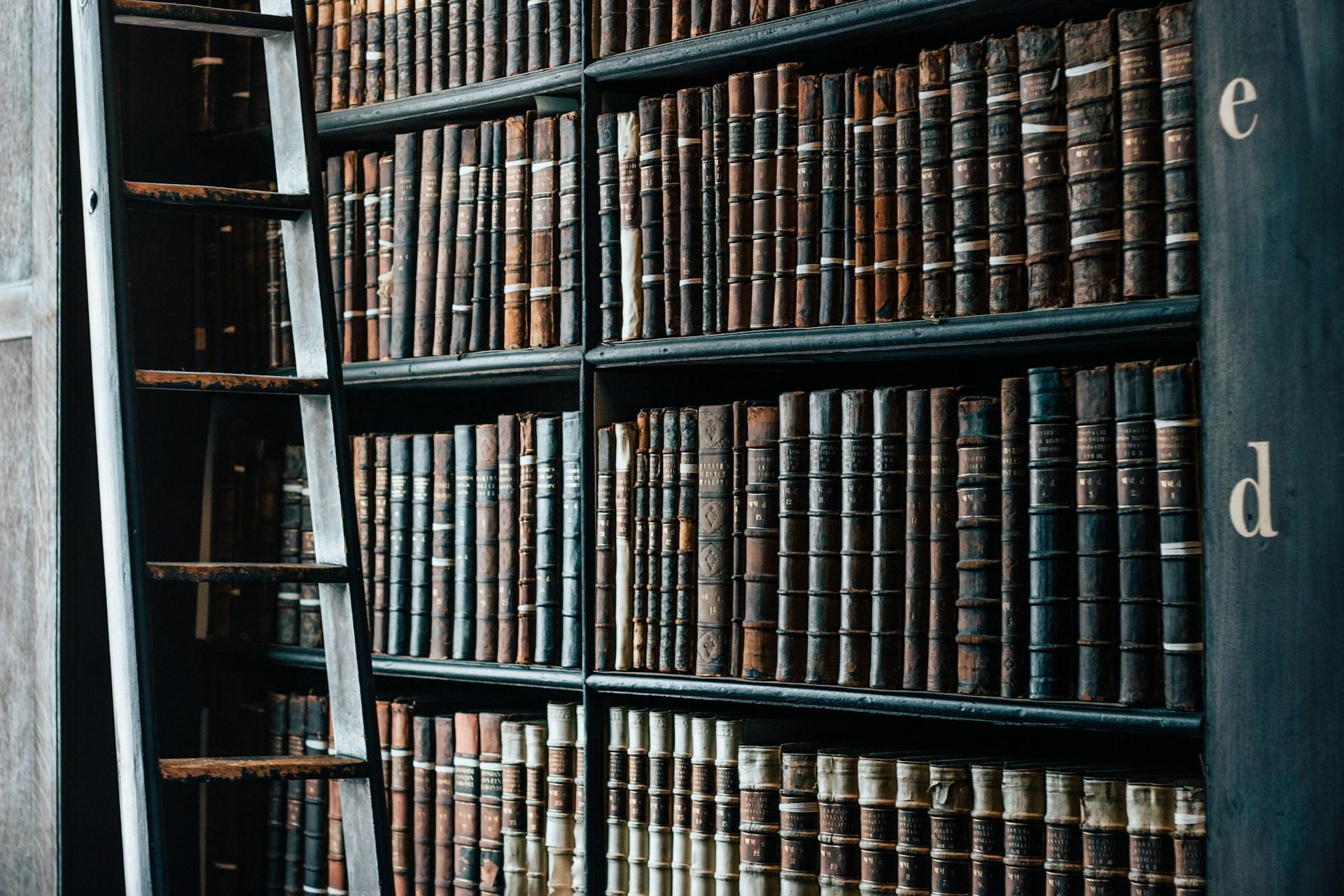 Books in a library with a ladder nearby