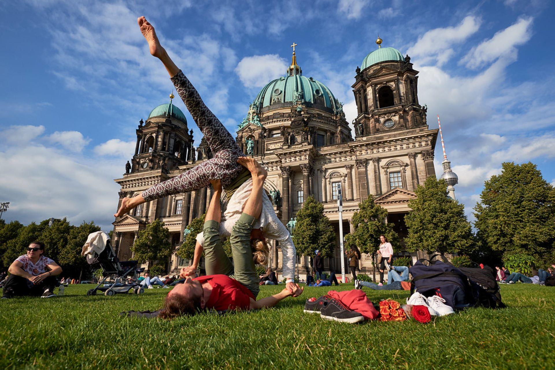 Couples learning AcroYoga postures in a park