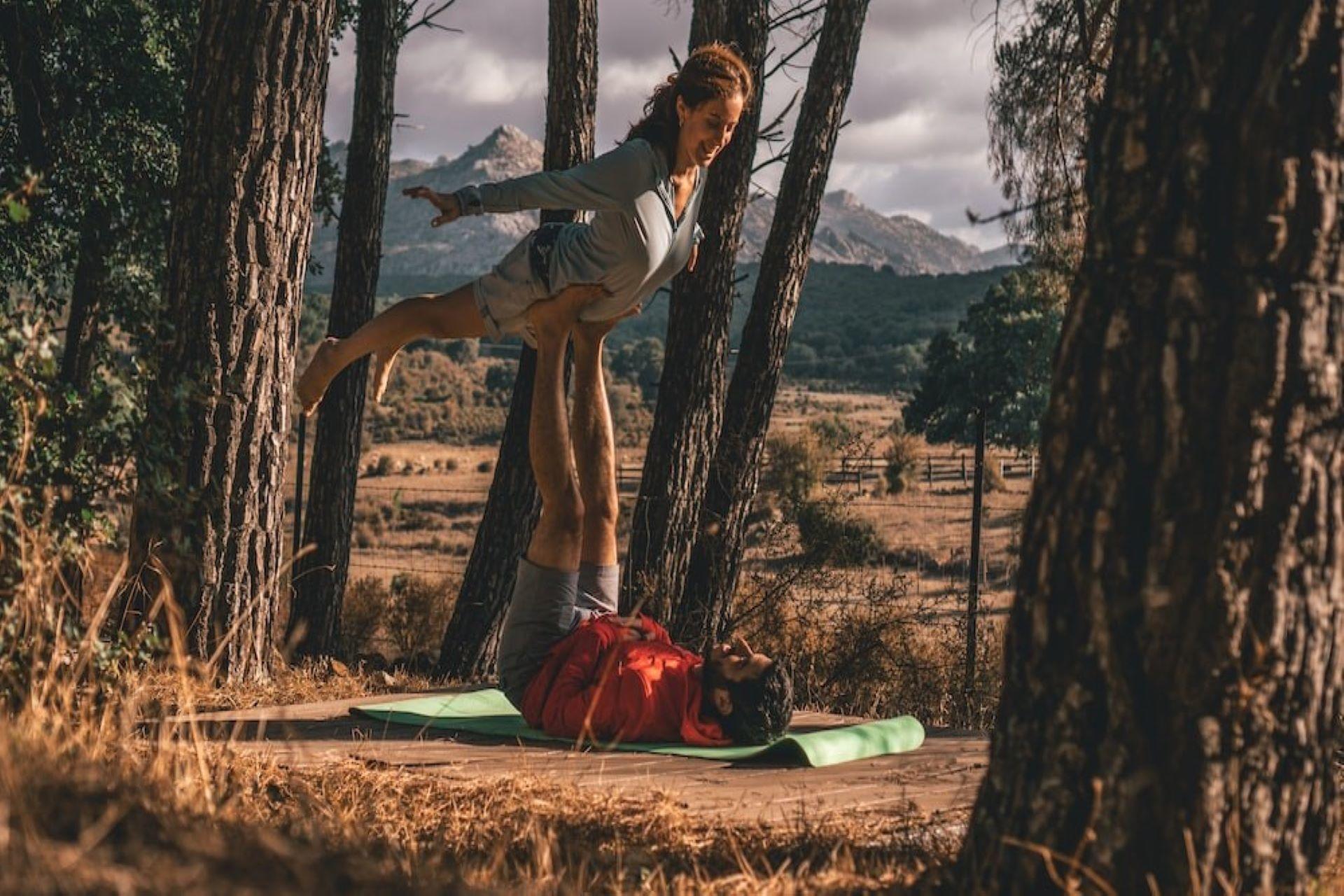 Partners practicing AcroYoga poses in the woods