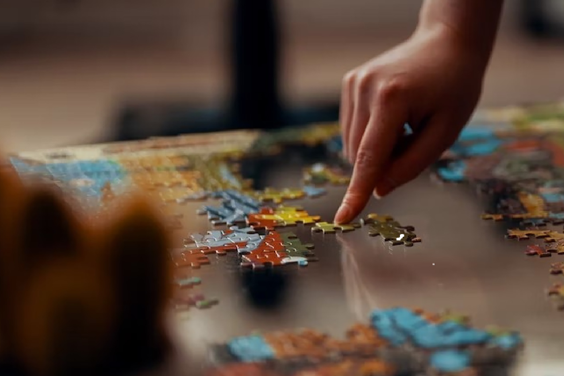 A person moving puzzle pieces across the table