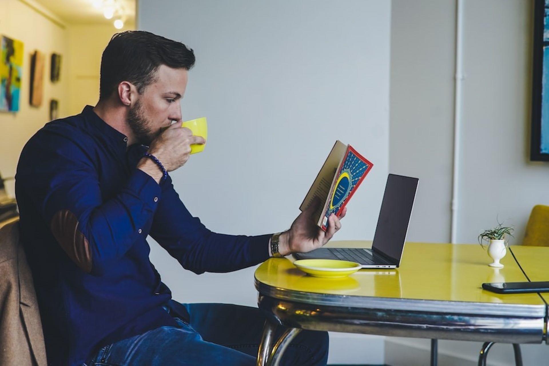 A man reading a book while drinking coffee