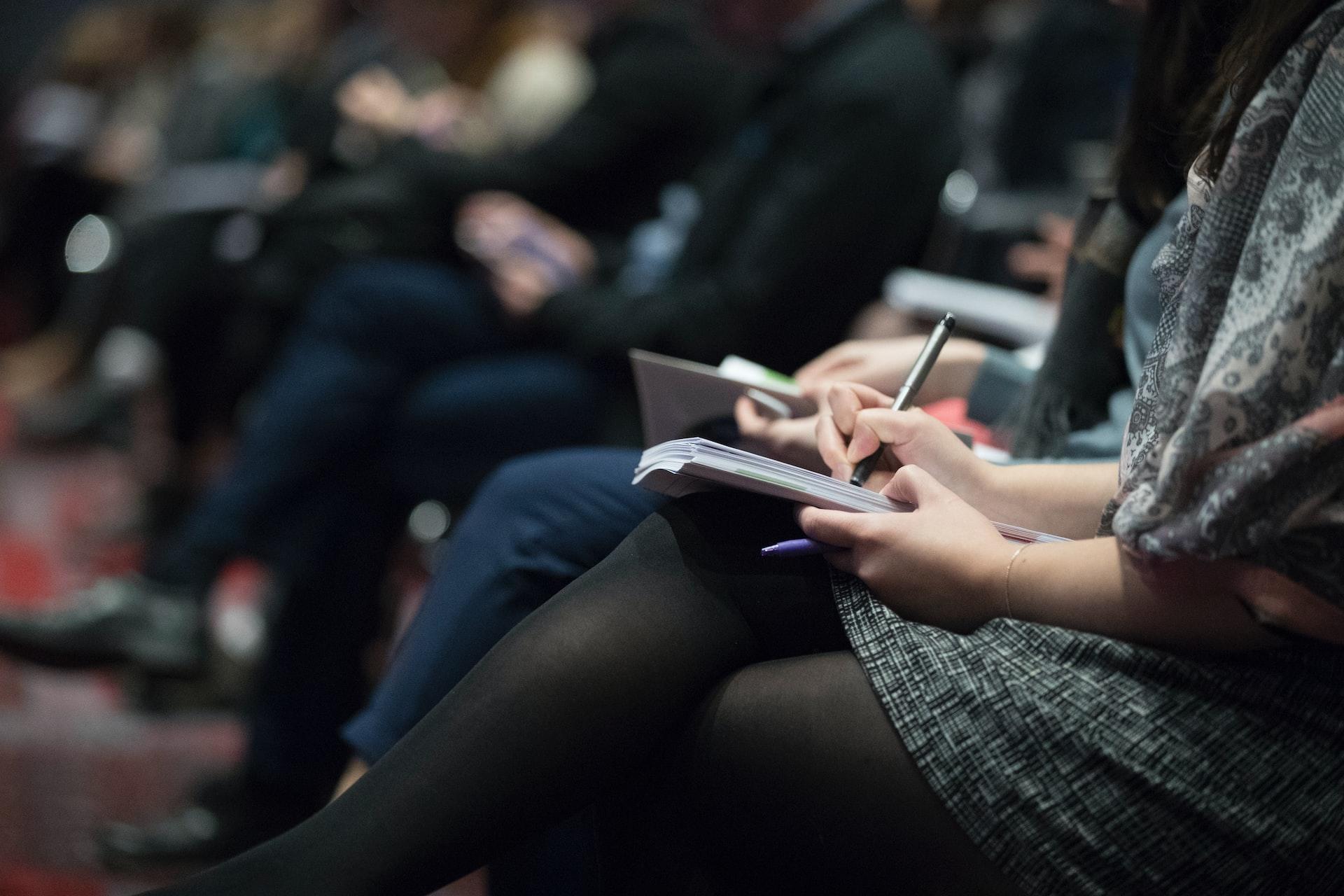 Conference attendees sitting with notepads
