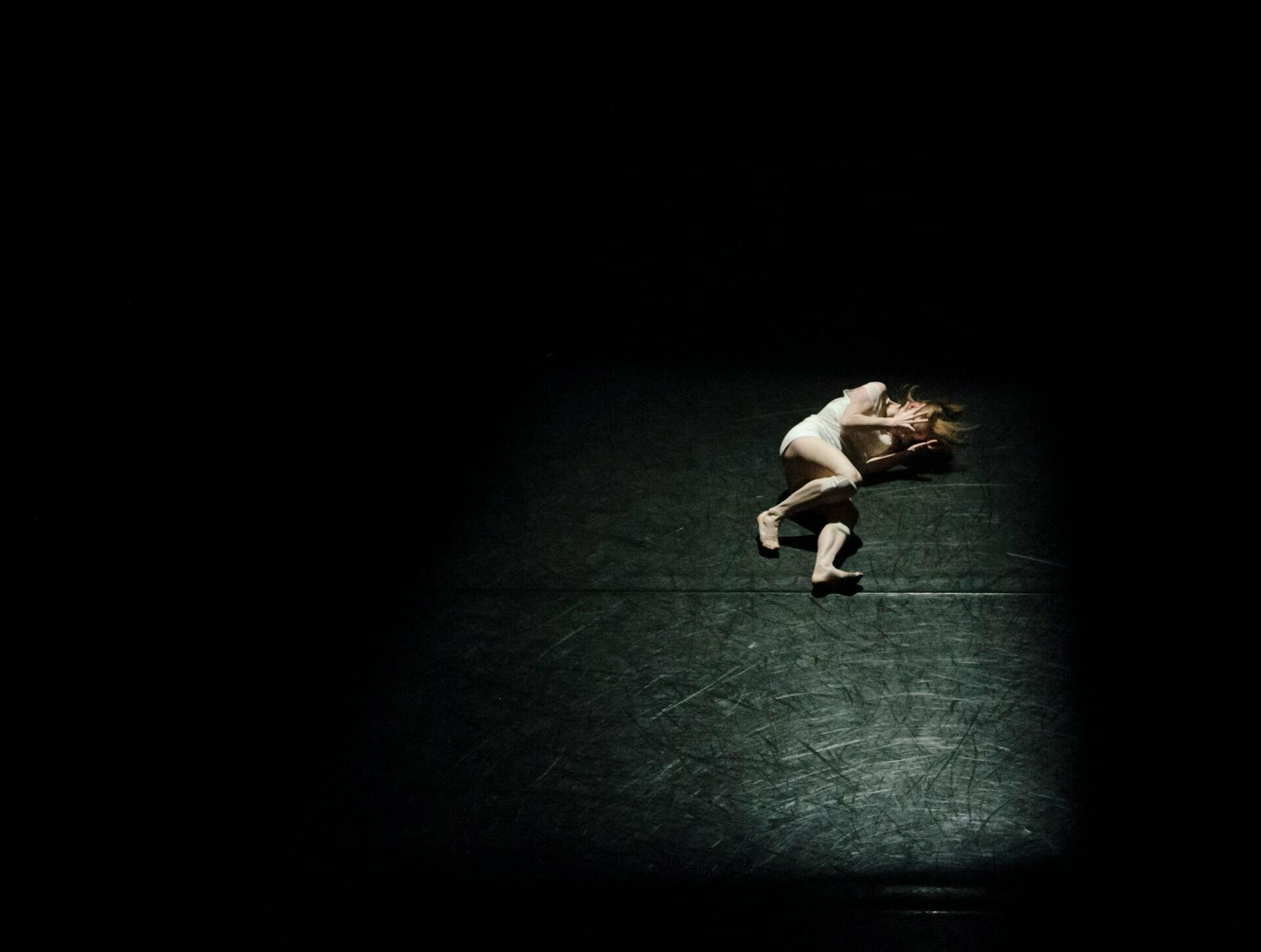 A dancer curled in a ball on stage.