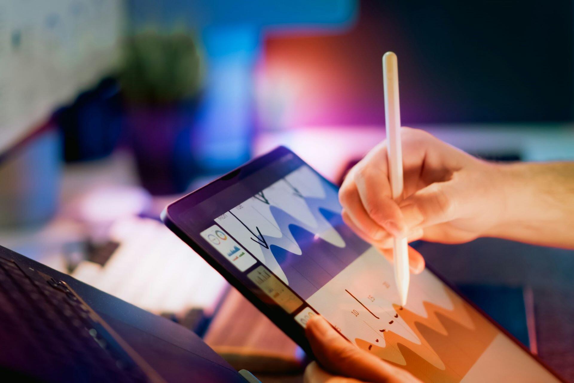 Person using a stylus to examine charts on a tablet
