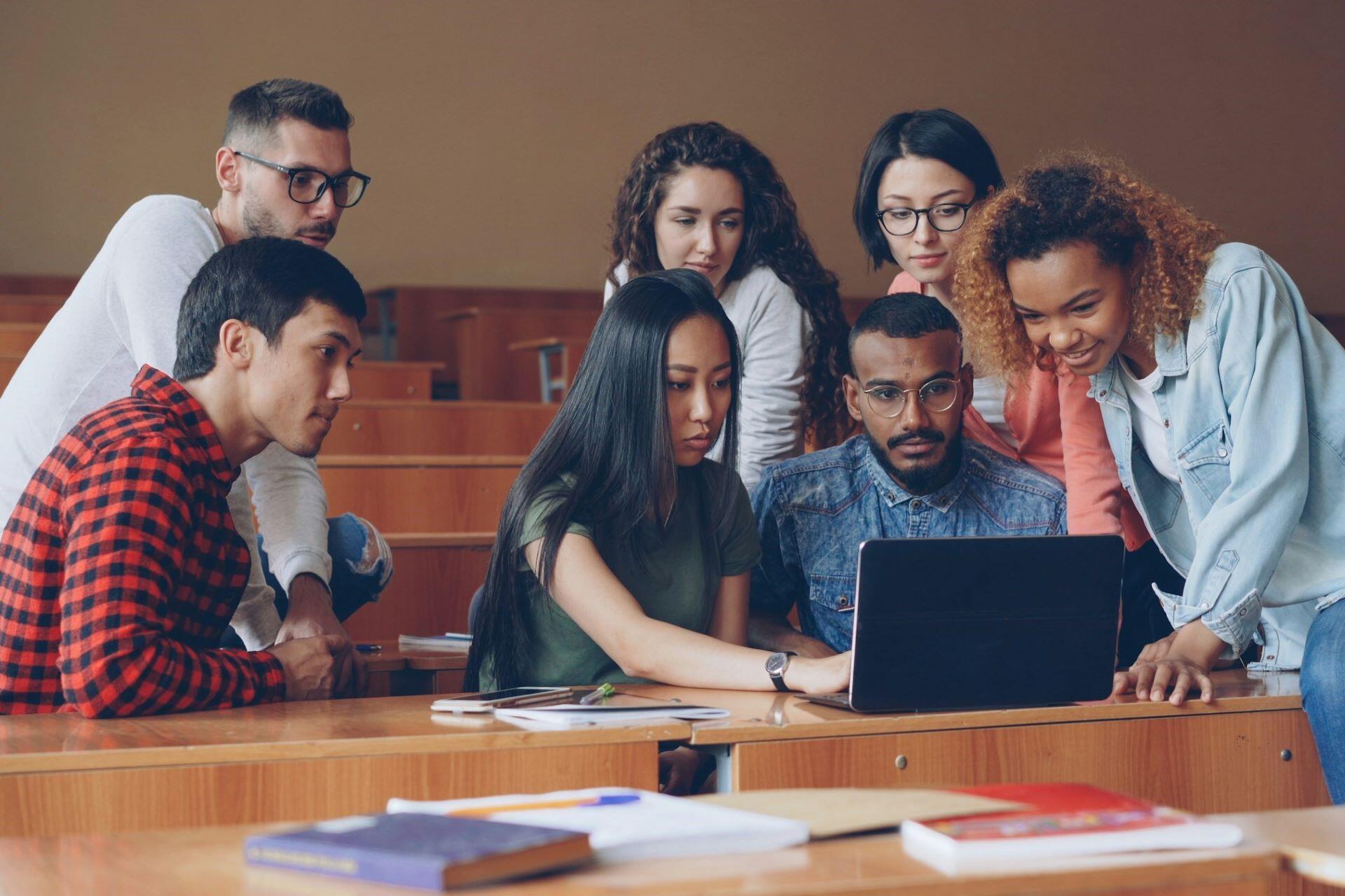 Group of college students working together around a laptop