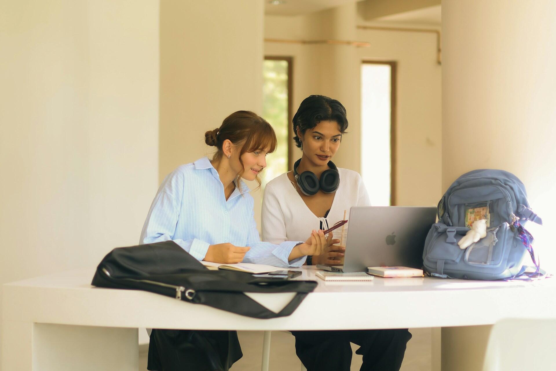 Two students working together with a laptop and notes