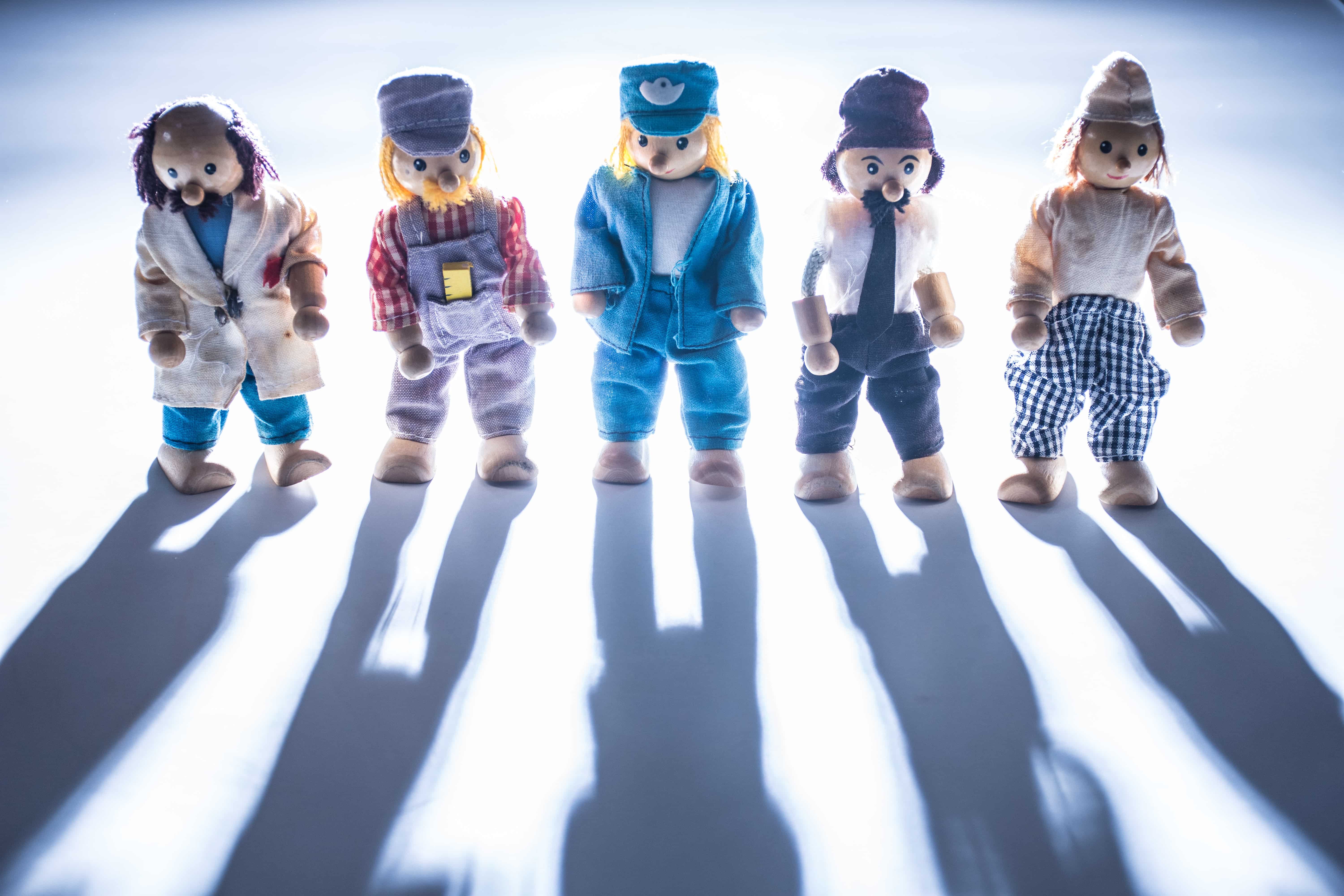 Five figurines dressed up in different trade uniforms.