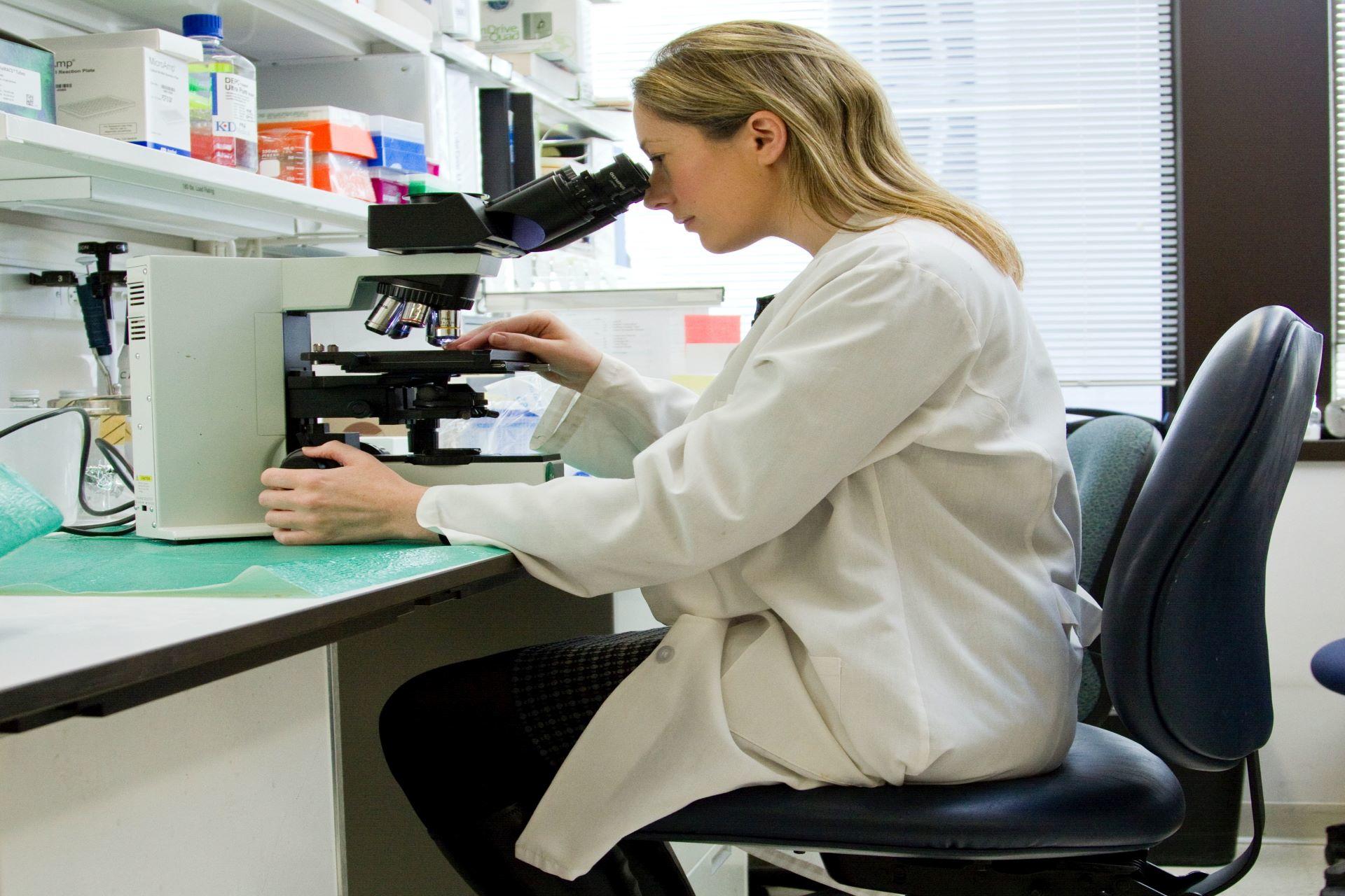 A pharmacist studying medicine samples through a microscope