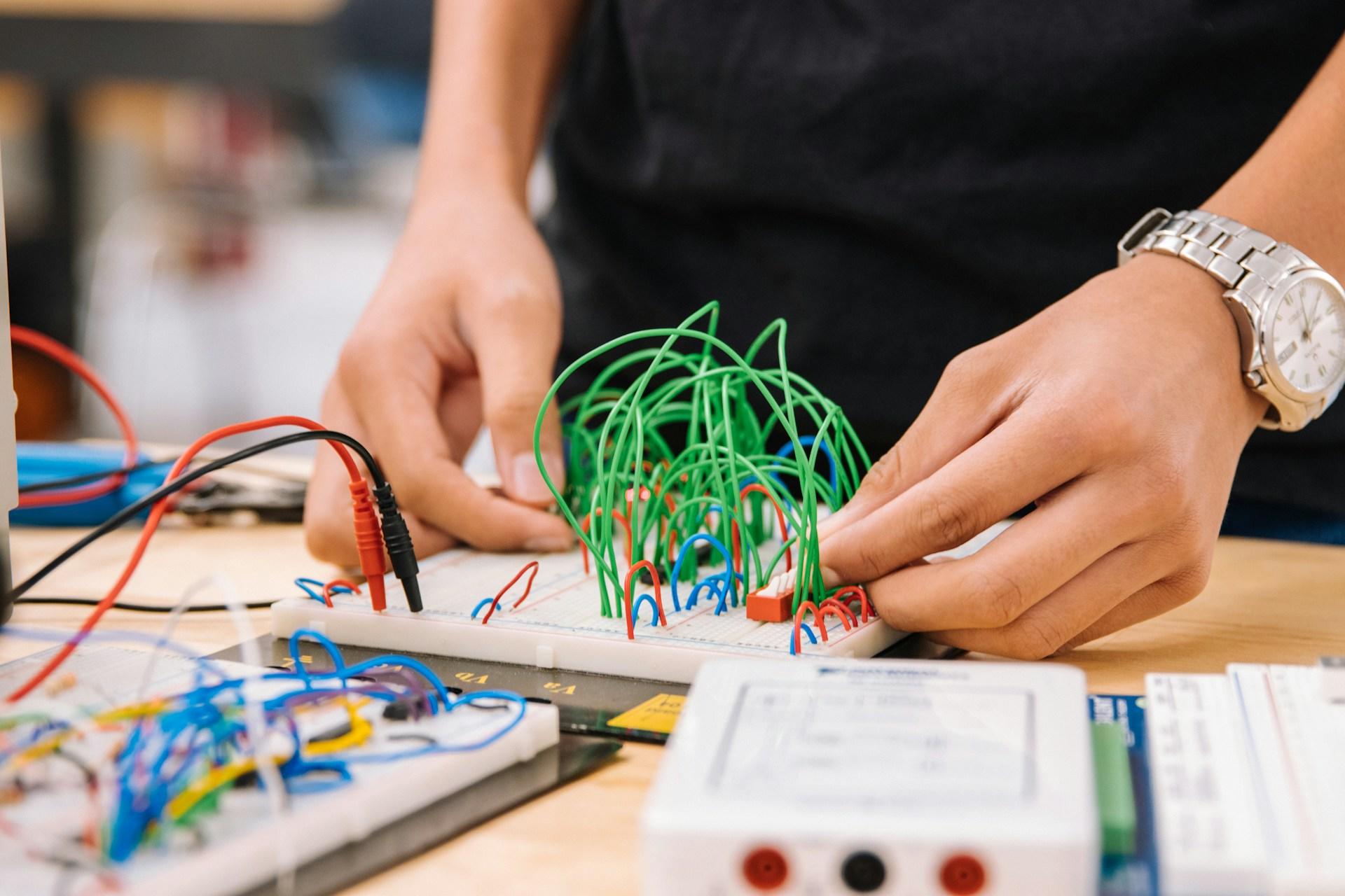 A person working on an electronics breadboard.