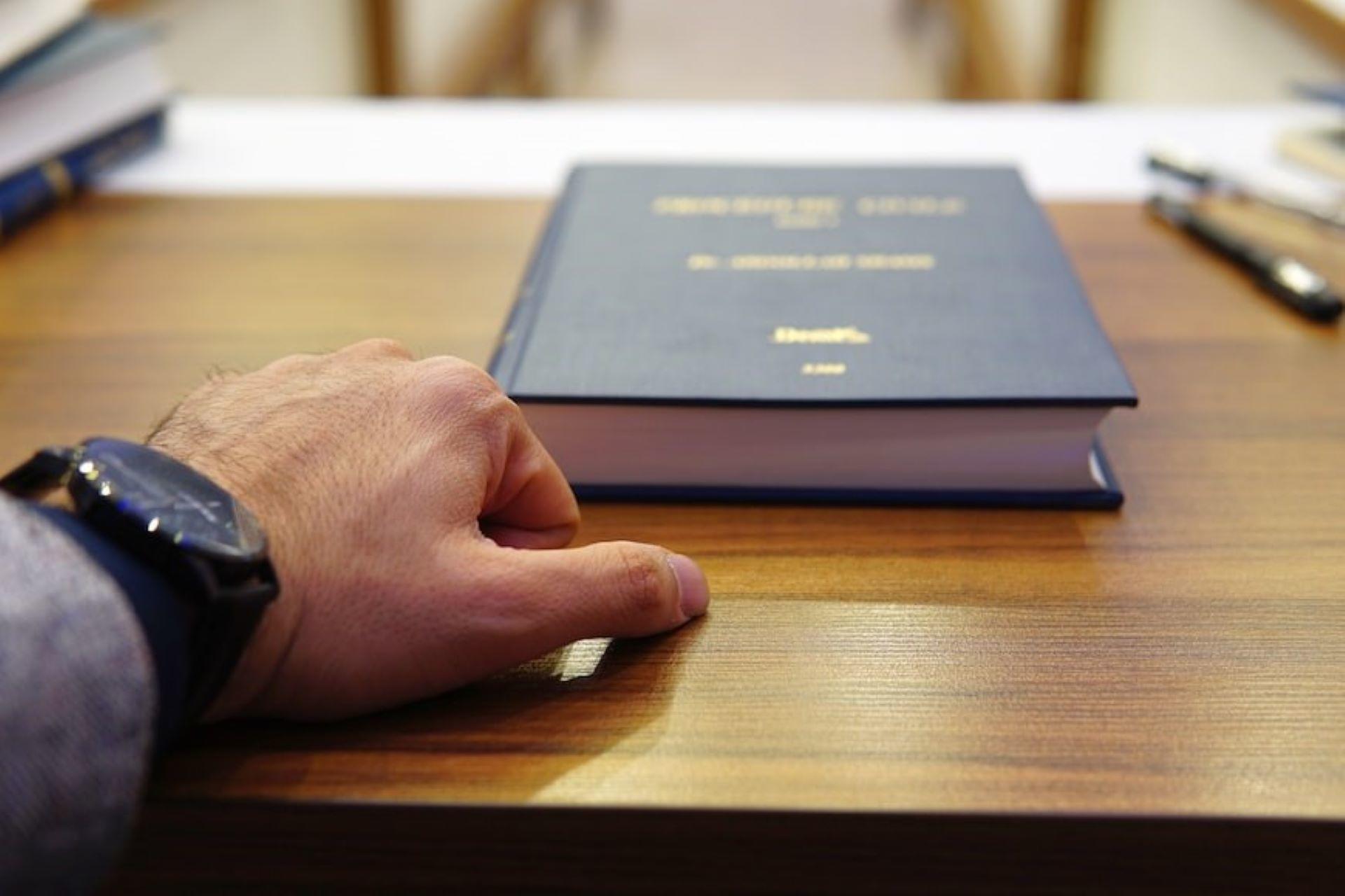 A law book and a hand on the table