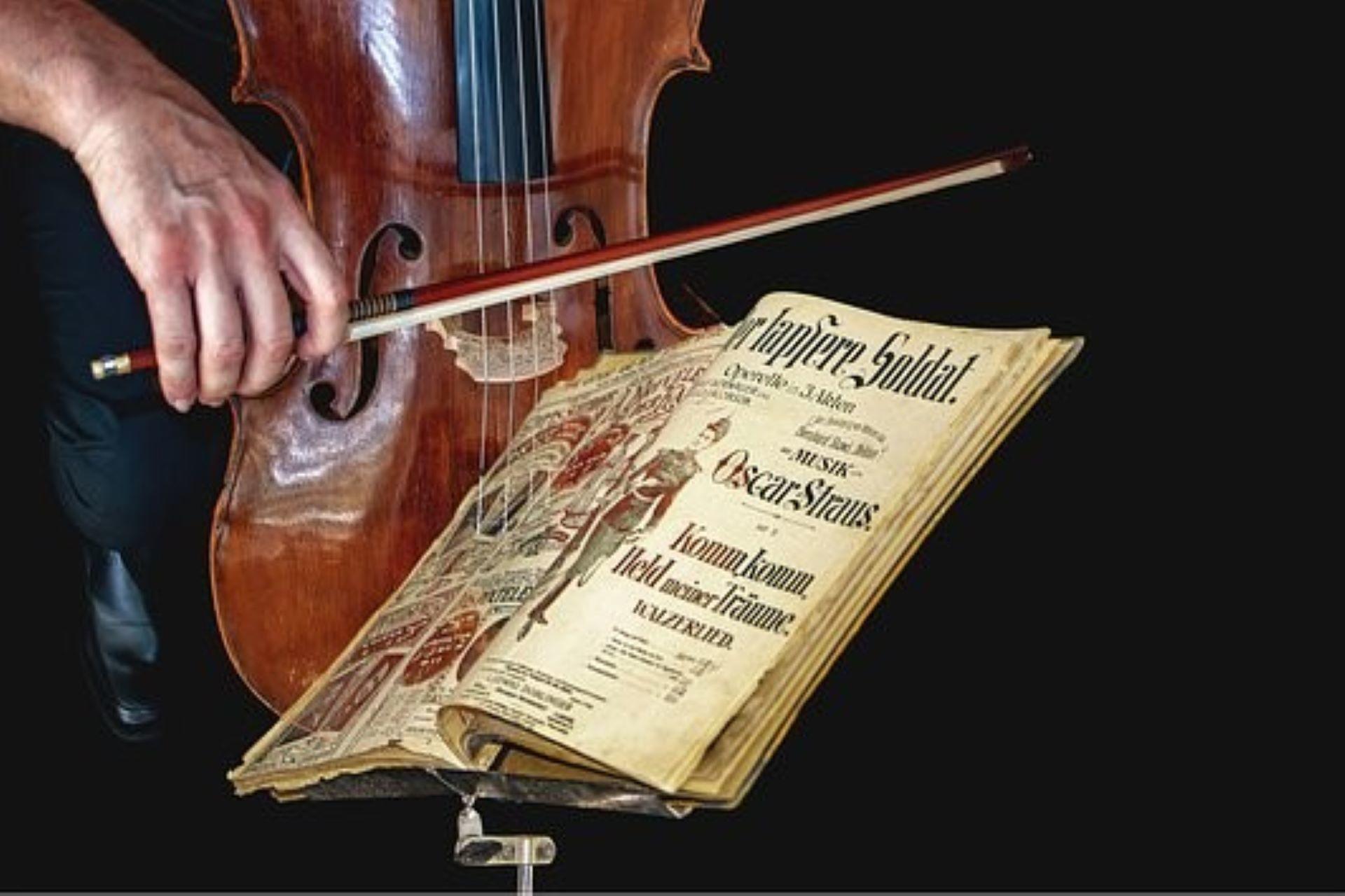 A violin being played alongside a music book.