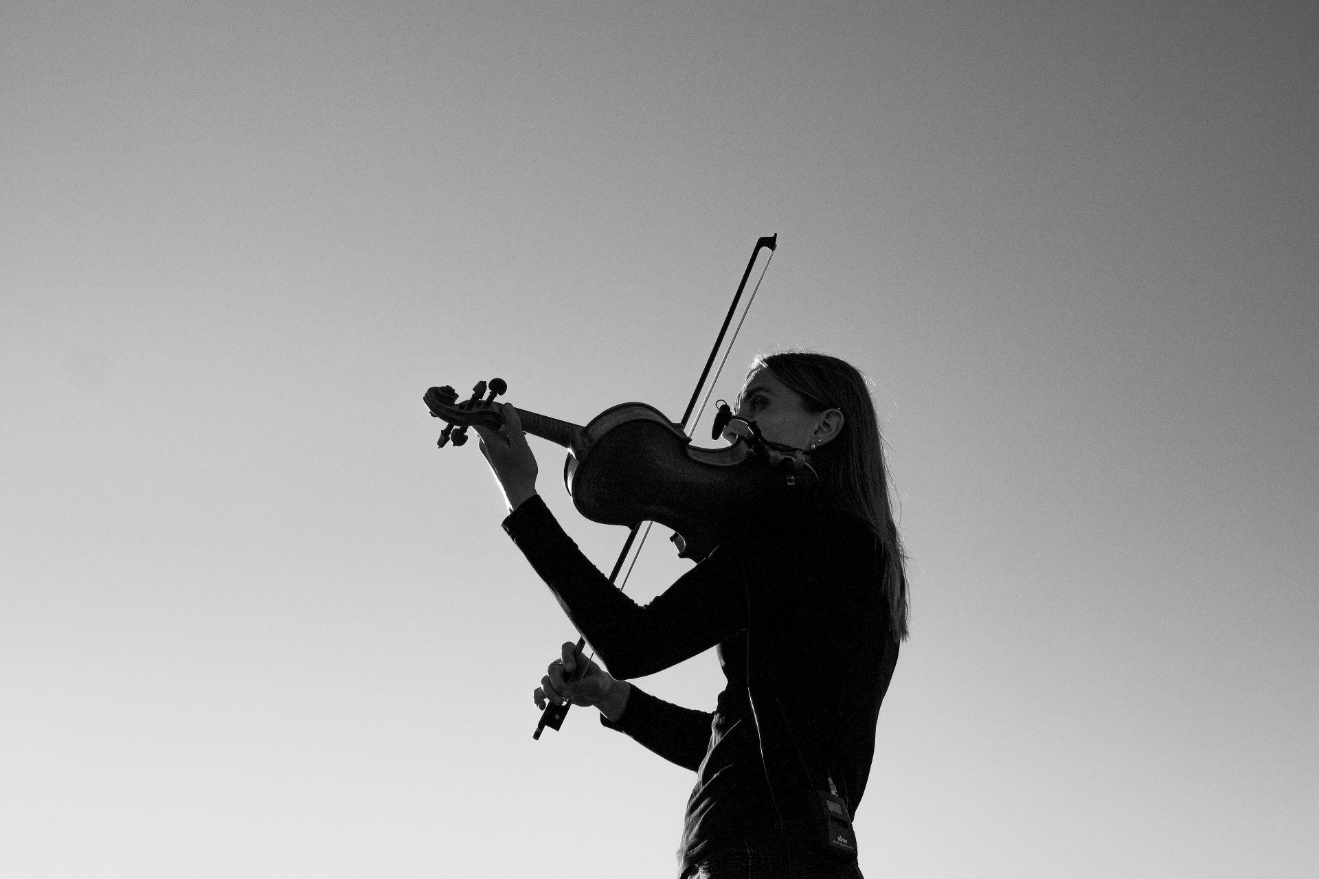 A violinist performing in a dim light room