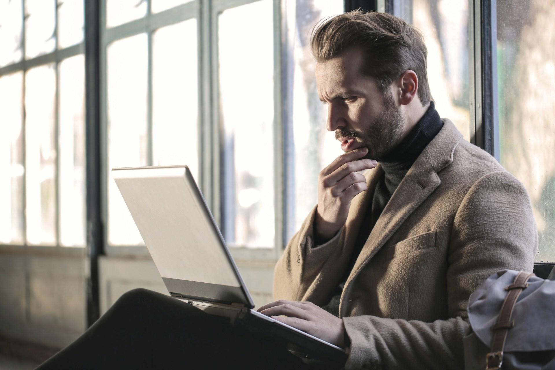man thinking while looking at laptop