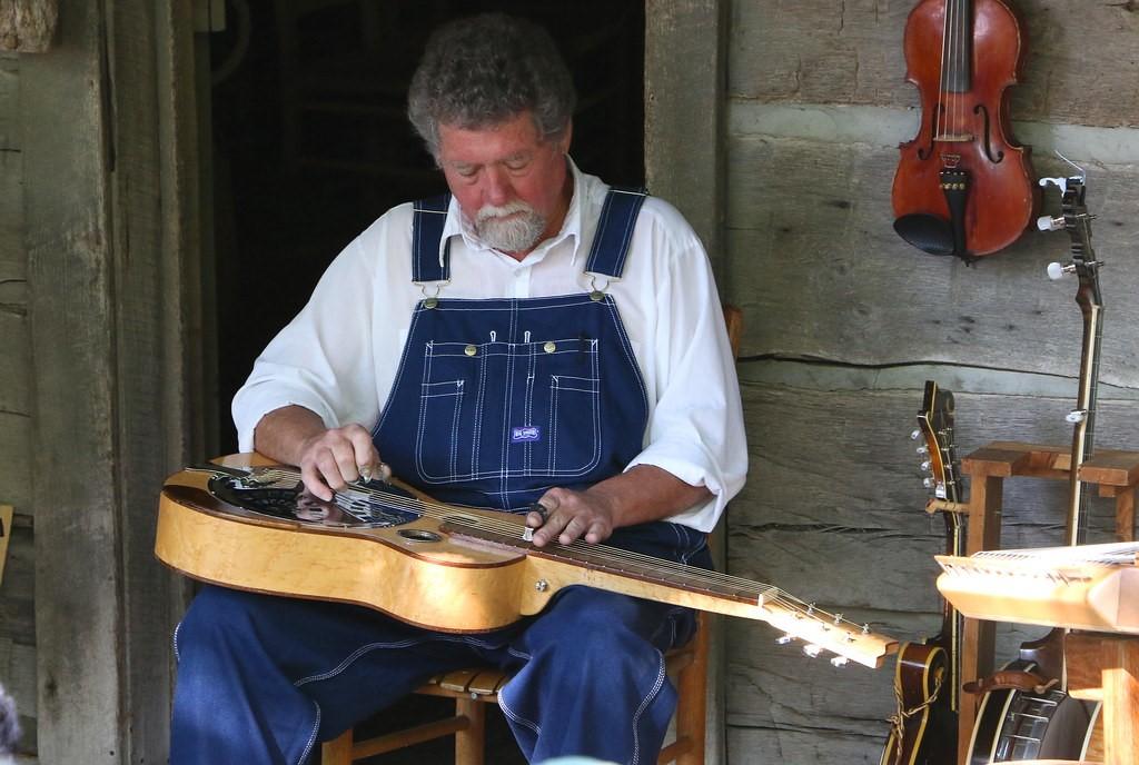 A man playing a resonator guitar in lap slide style.