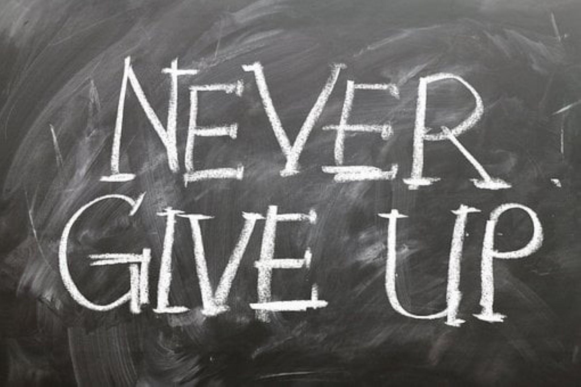 A blackboard displaying "Never Give Up."