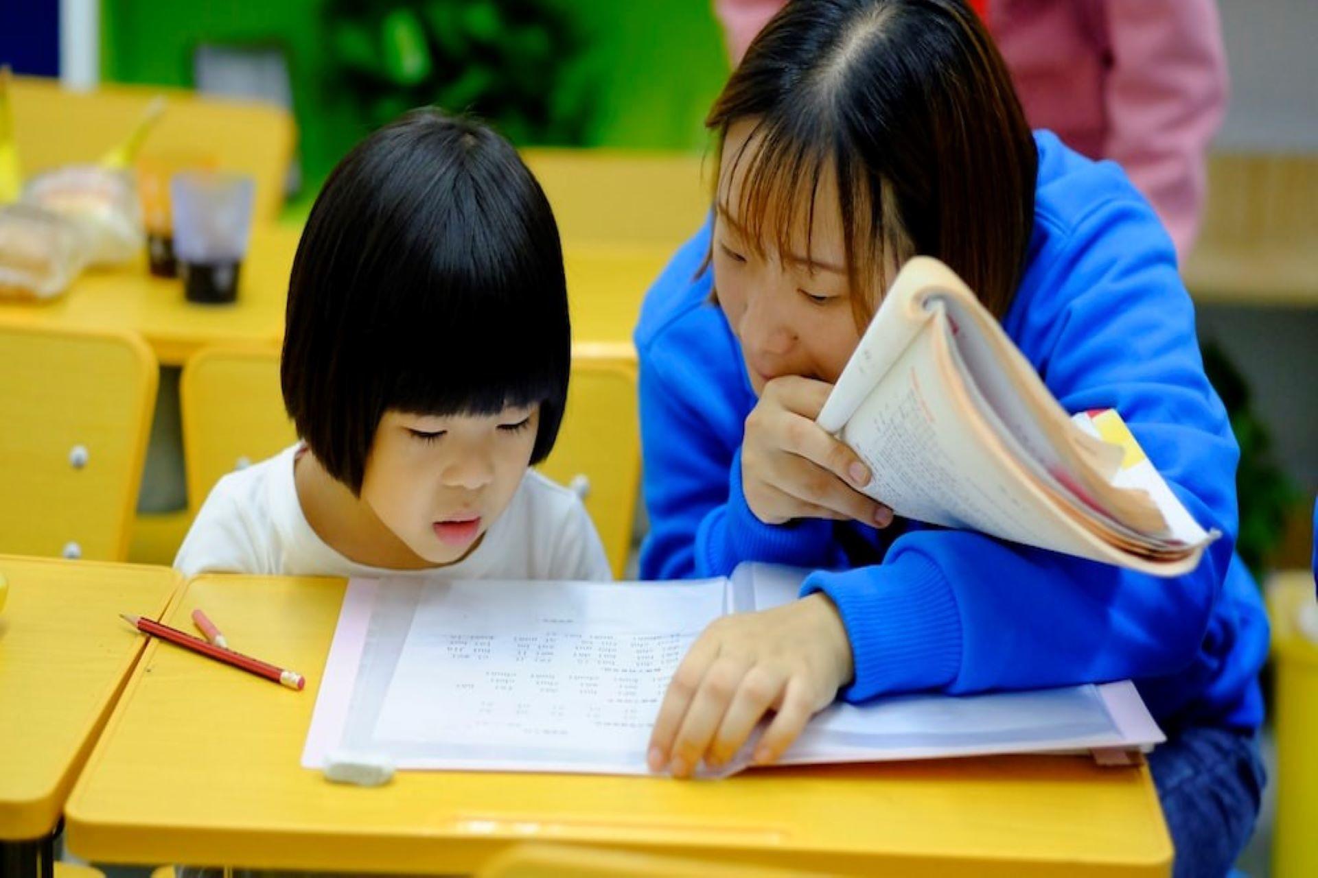 A female tutor teaching a little girl.