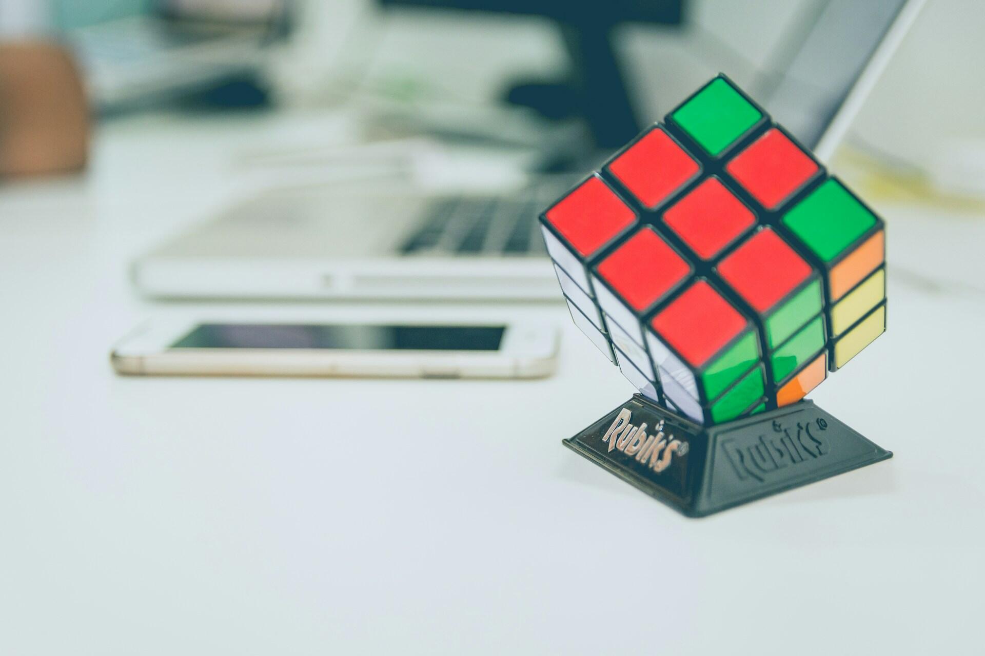 an unsolved rubik's cube in a stand on a desk