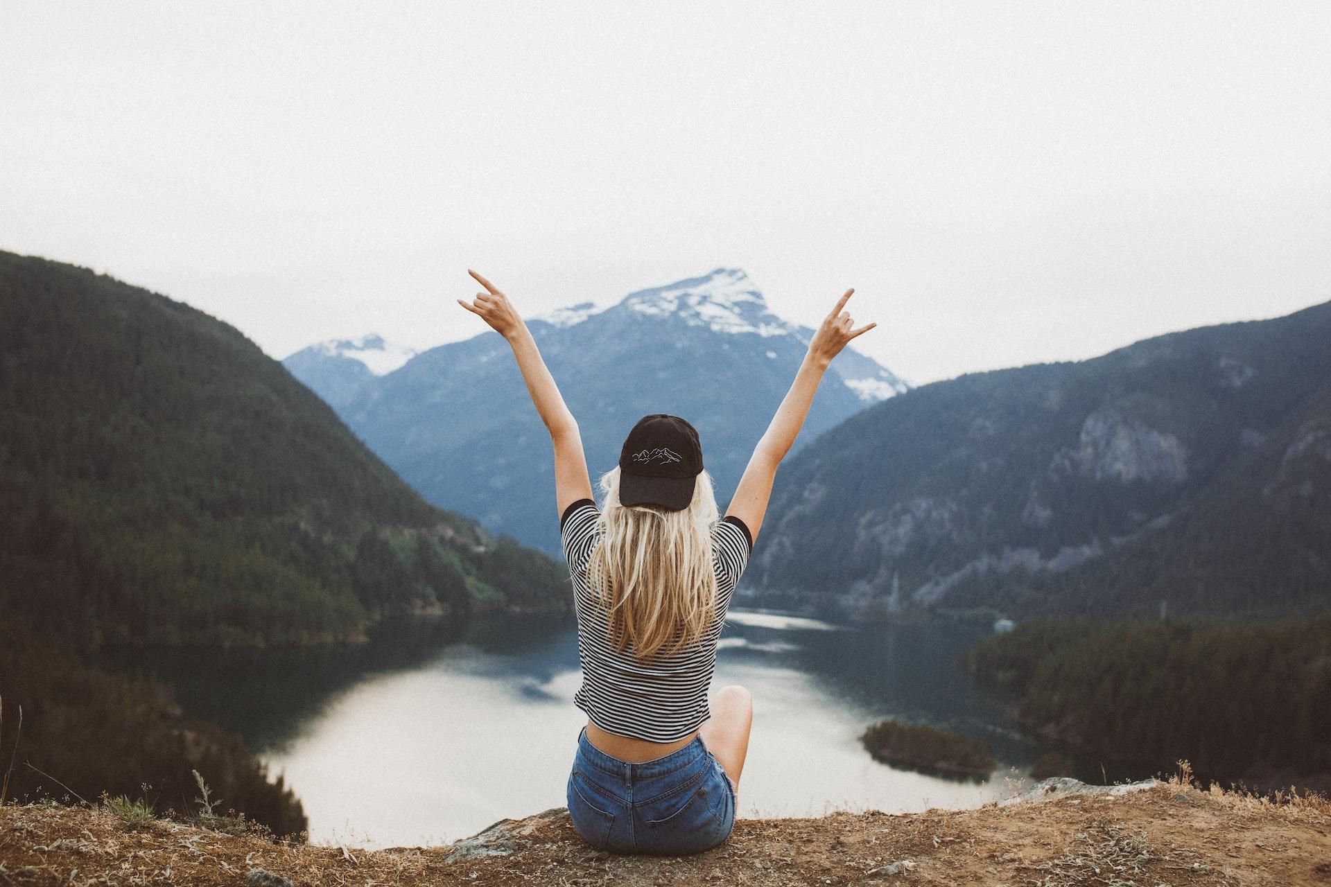 A woman sitting by a lake in the mountains