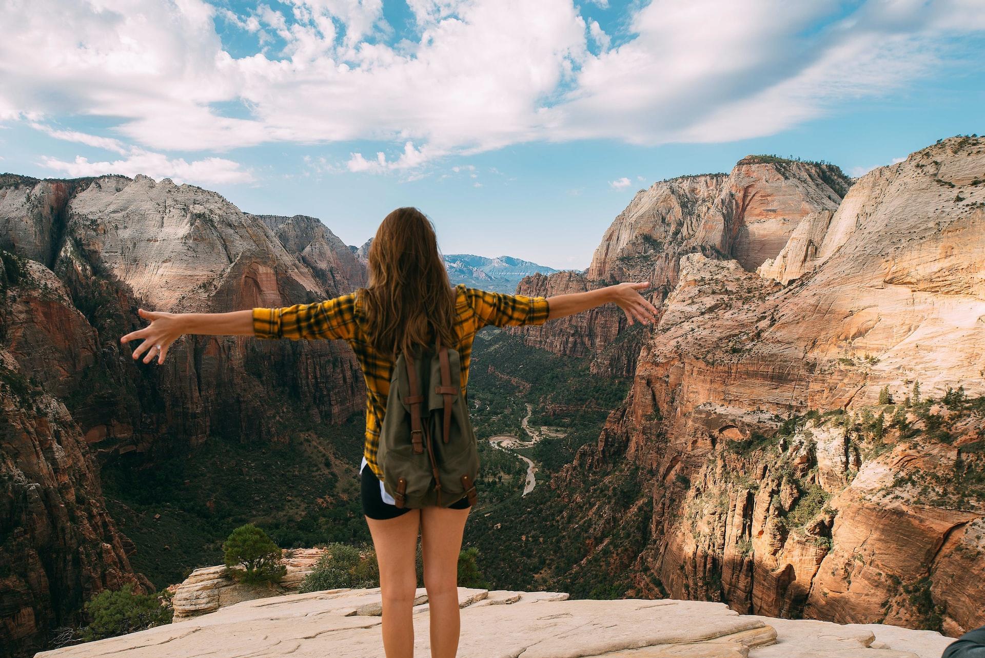 A woman standing with her arms open in front of a canyon