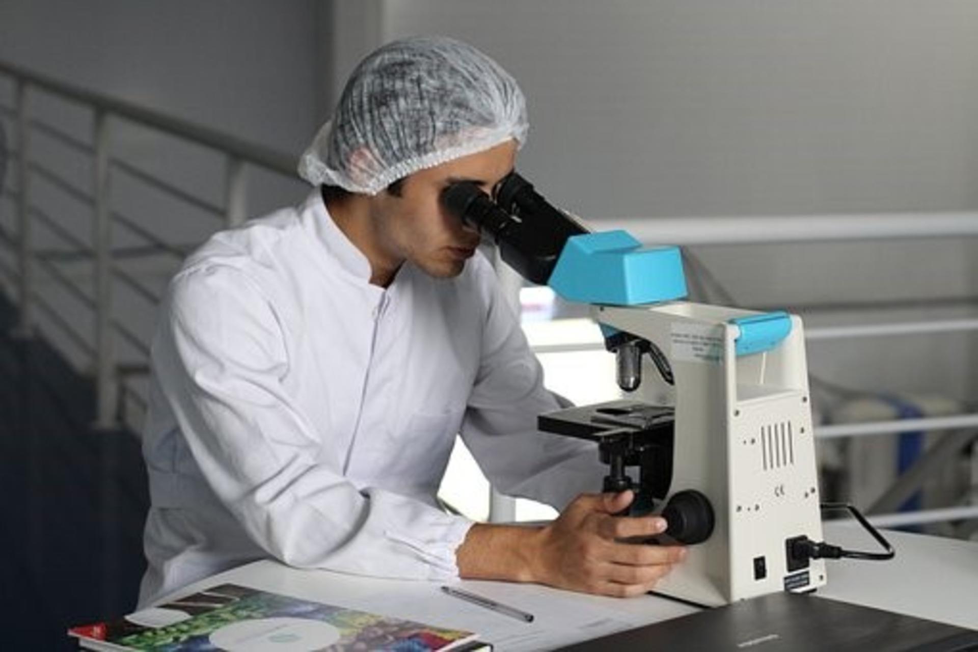 A chemist observing a specimen under the microscope. 