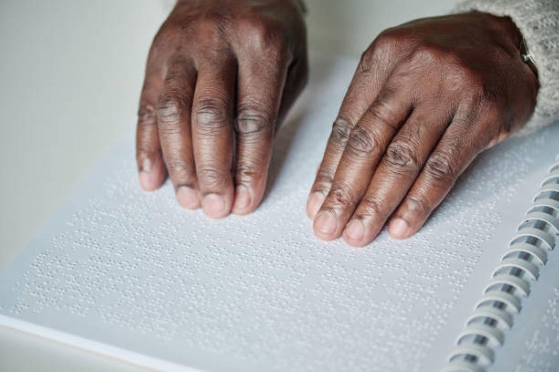 A visually impaired African American reading literature in Braille