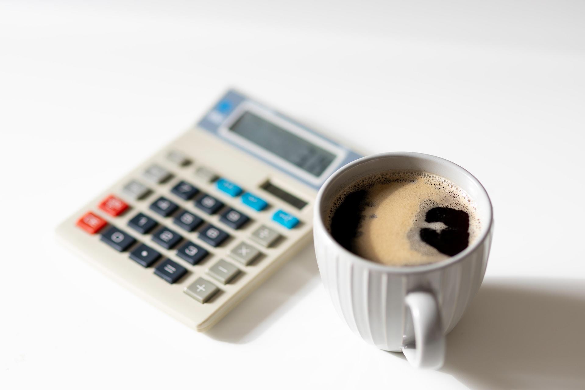 A cup of coffee next to a calculator.