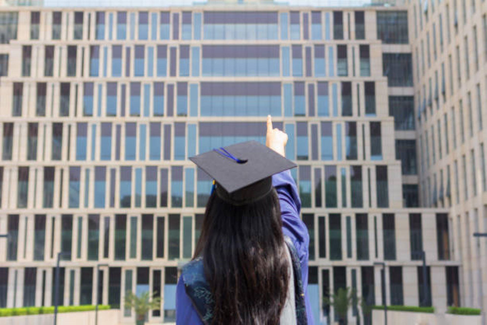 An African American graduate pointing at the building