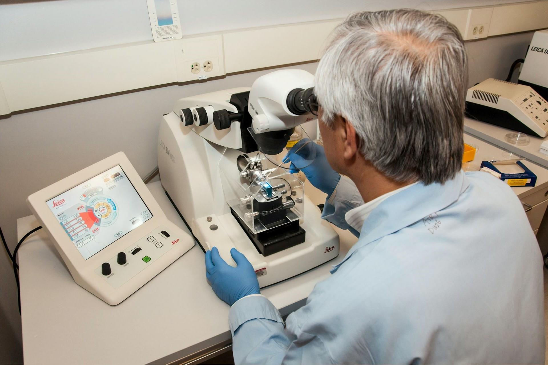 A scientist looking at a sample through a microscope.