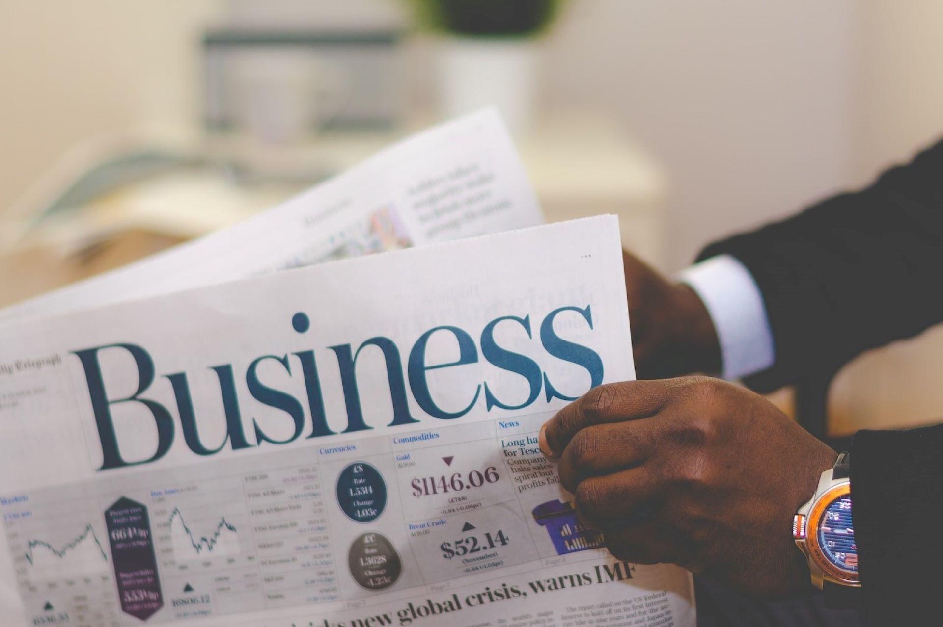 A person reading the business section of a newspaper.