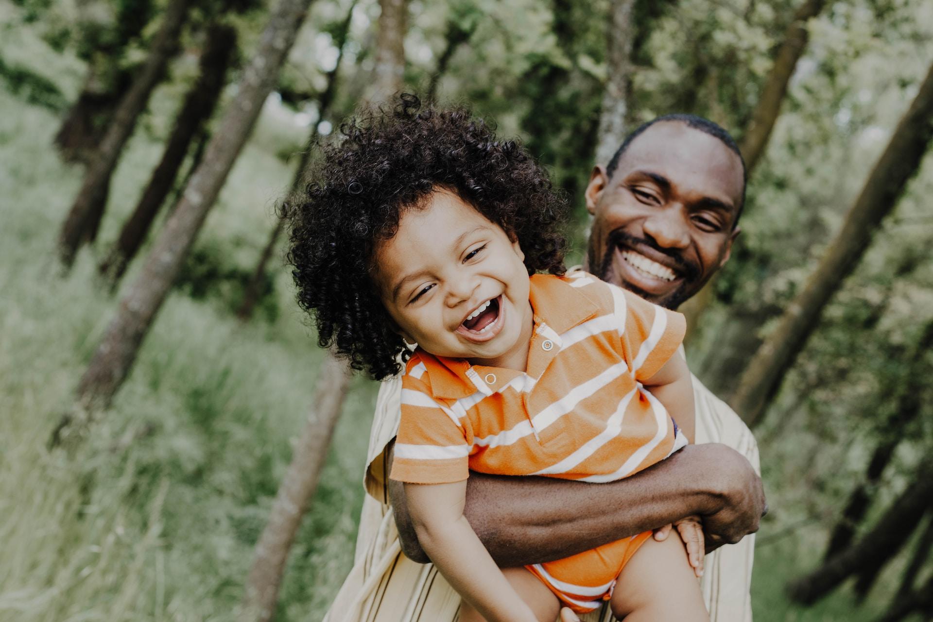 Father and daughter laughing in the woods.