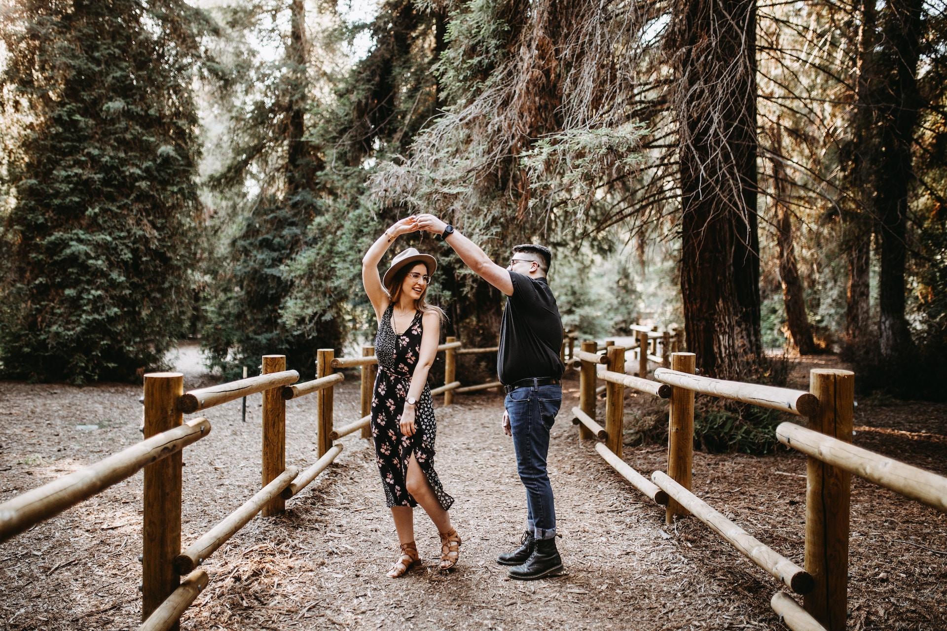 A young couple dances together in a natural setting.