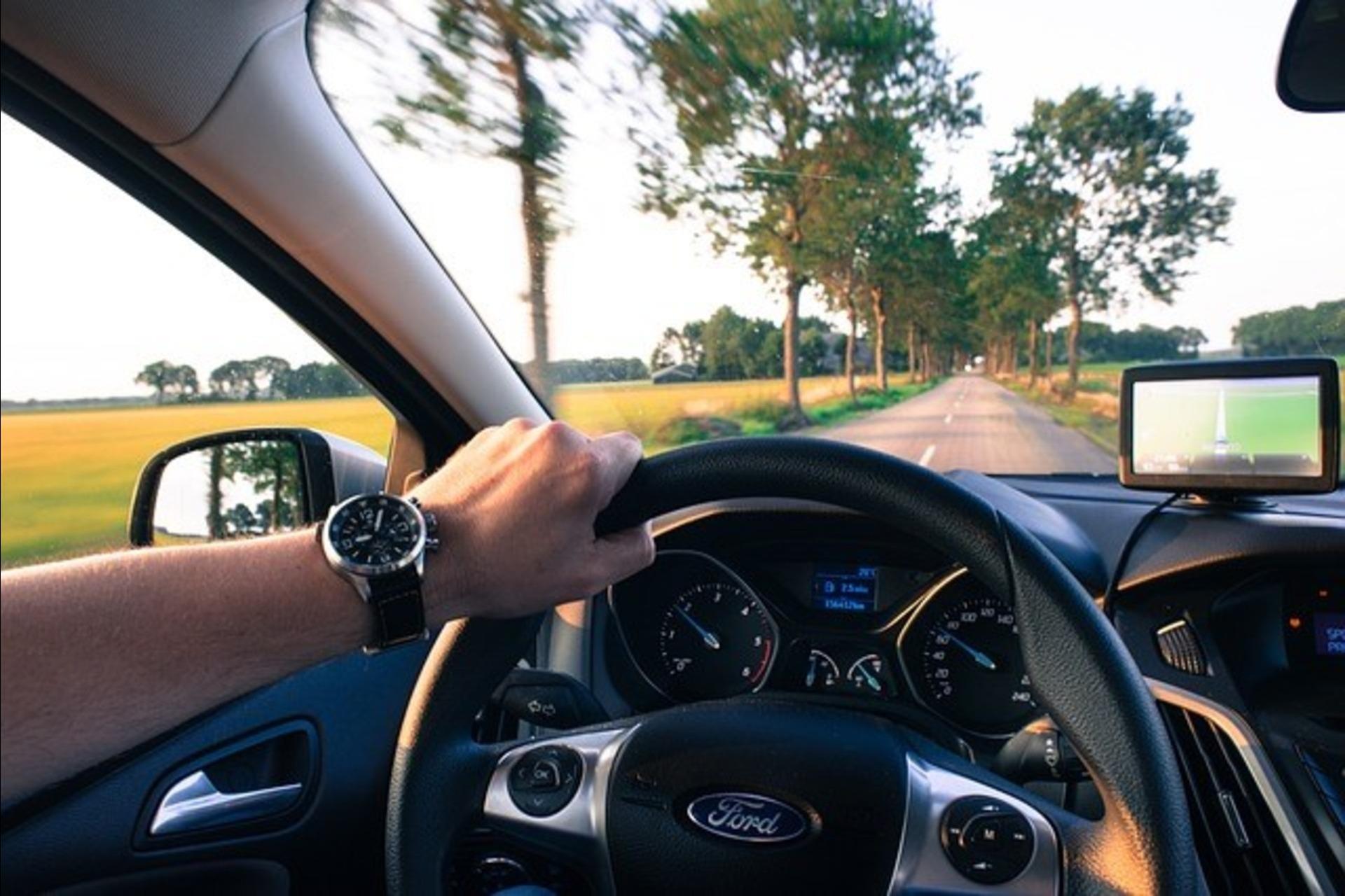 A man driving a Ford with the help of navigation.