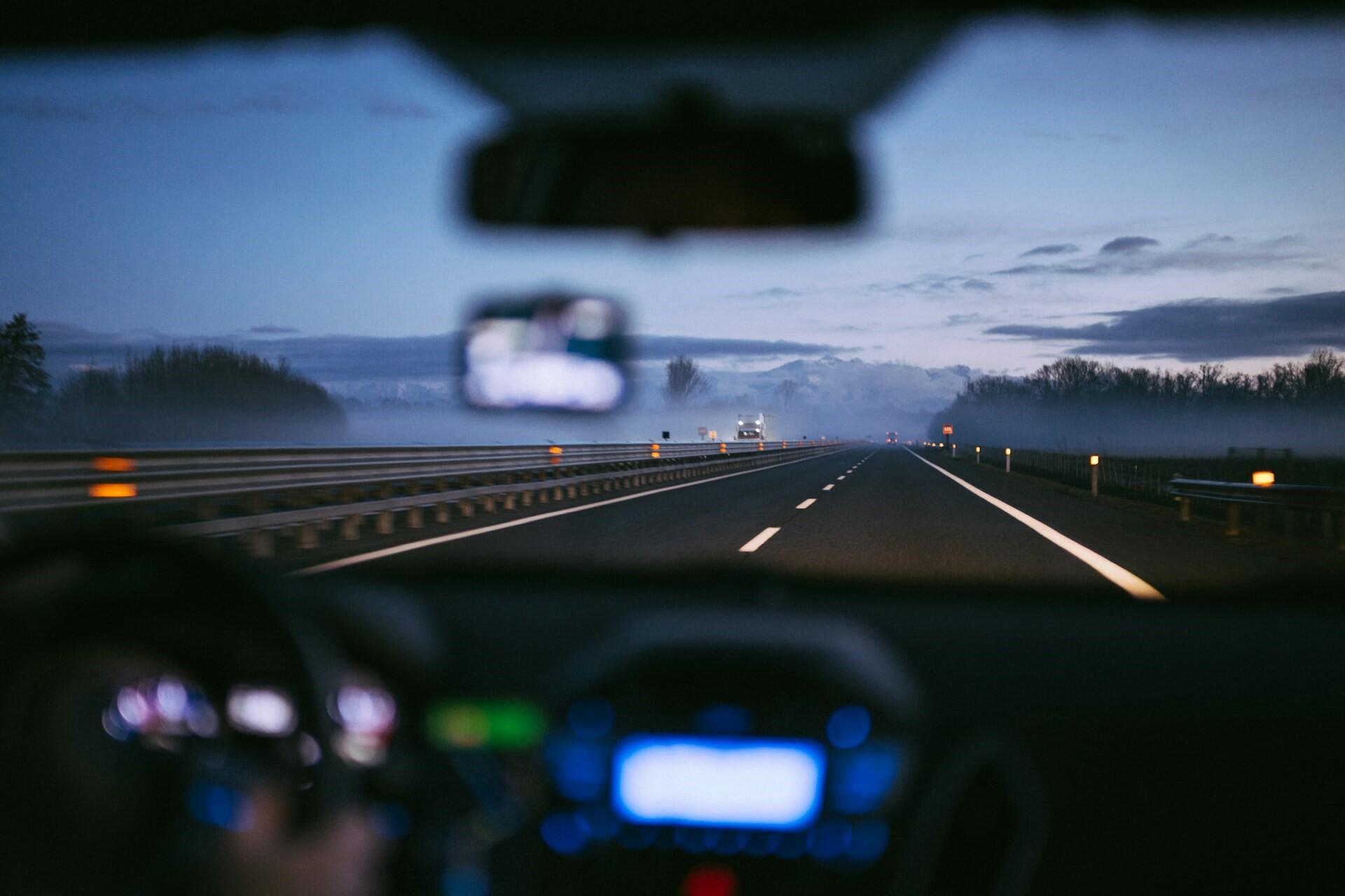 A car driving on a highway either at dawn or dusk.