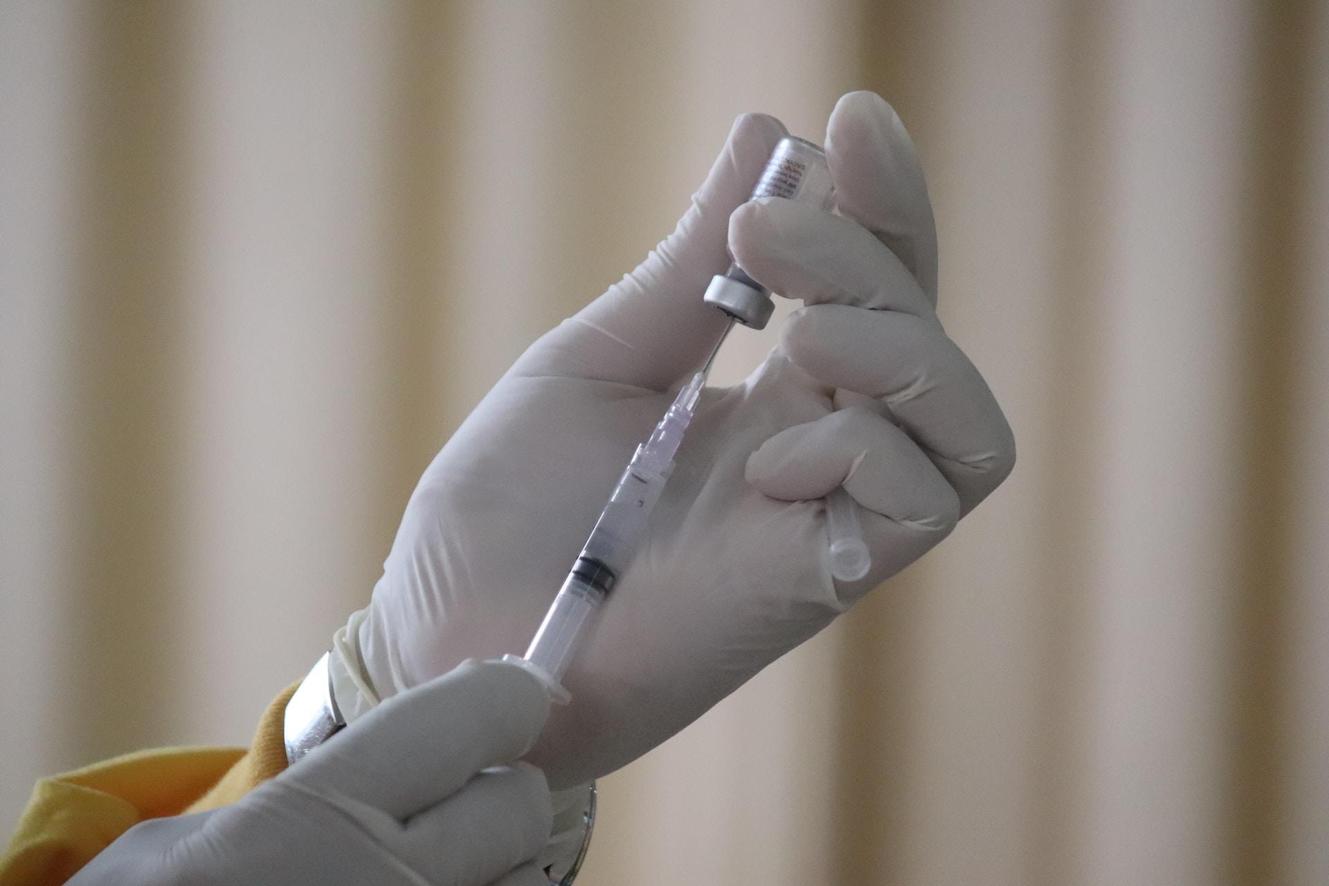 A gloved hand preparing a vaccine.
