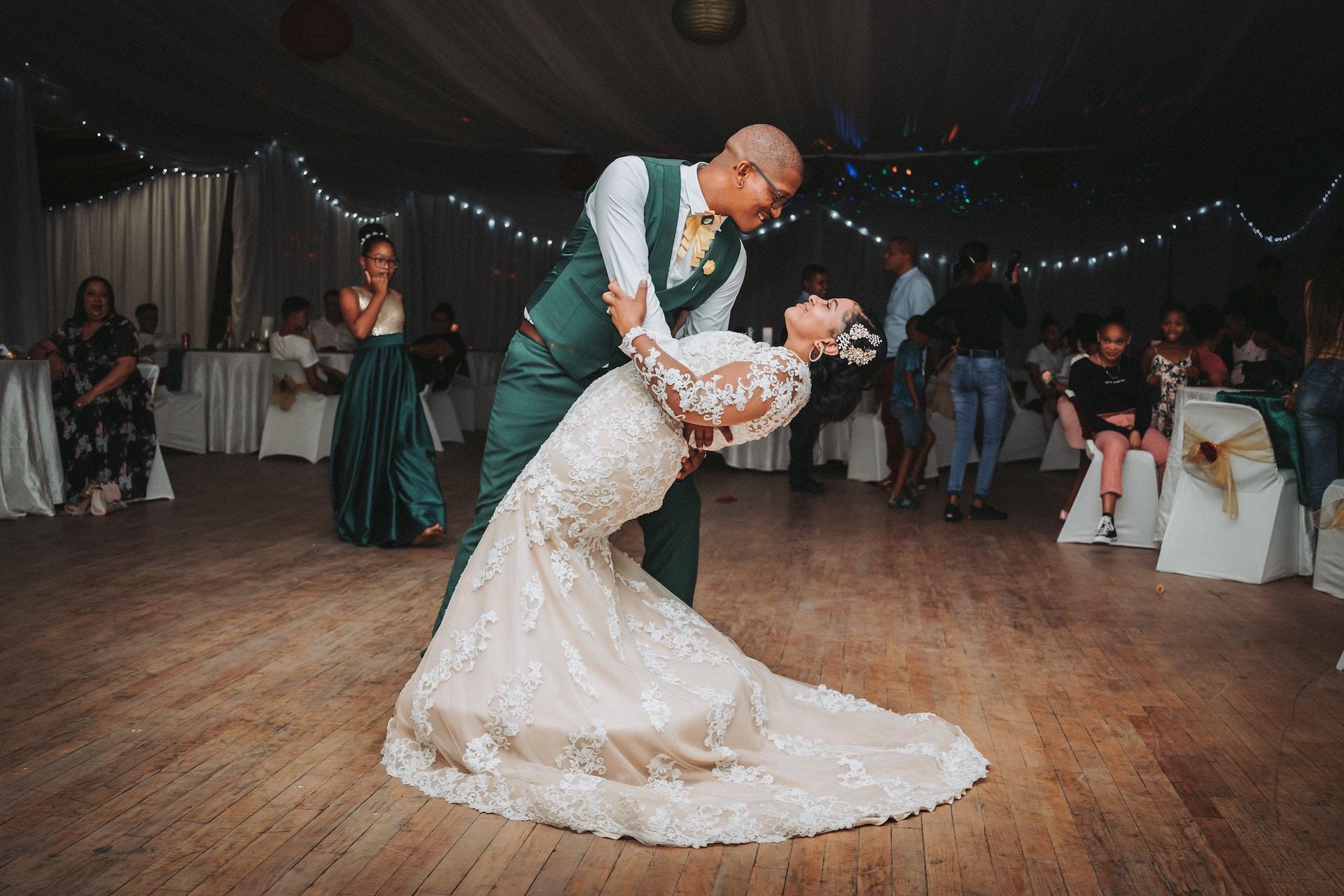 Newlyweds in their wedding clothes dance on the dancefloor.
