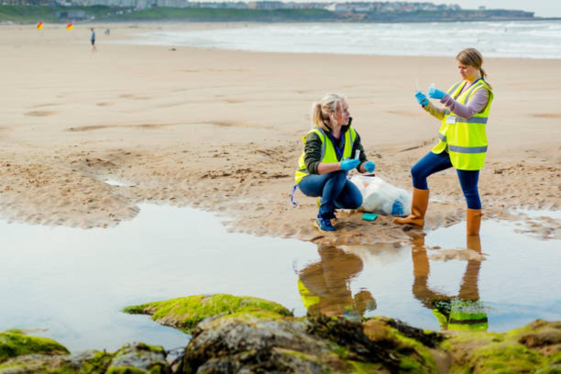 Two females water collecting and analyzing samples on the beach
