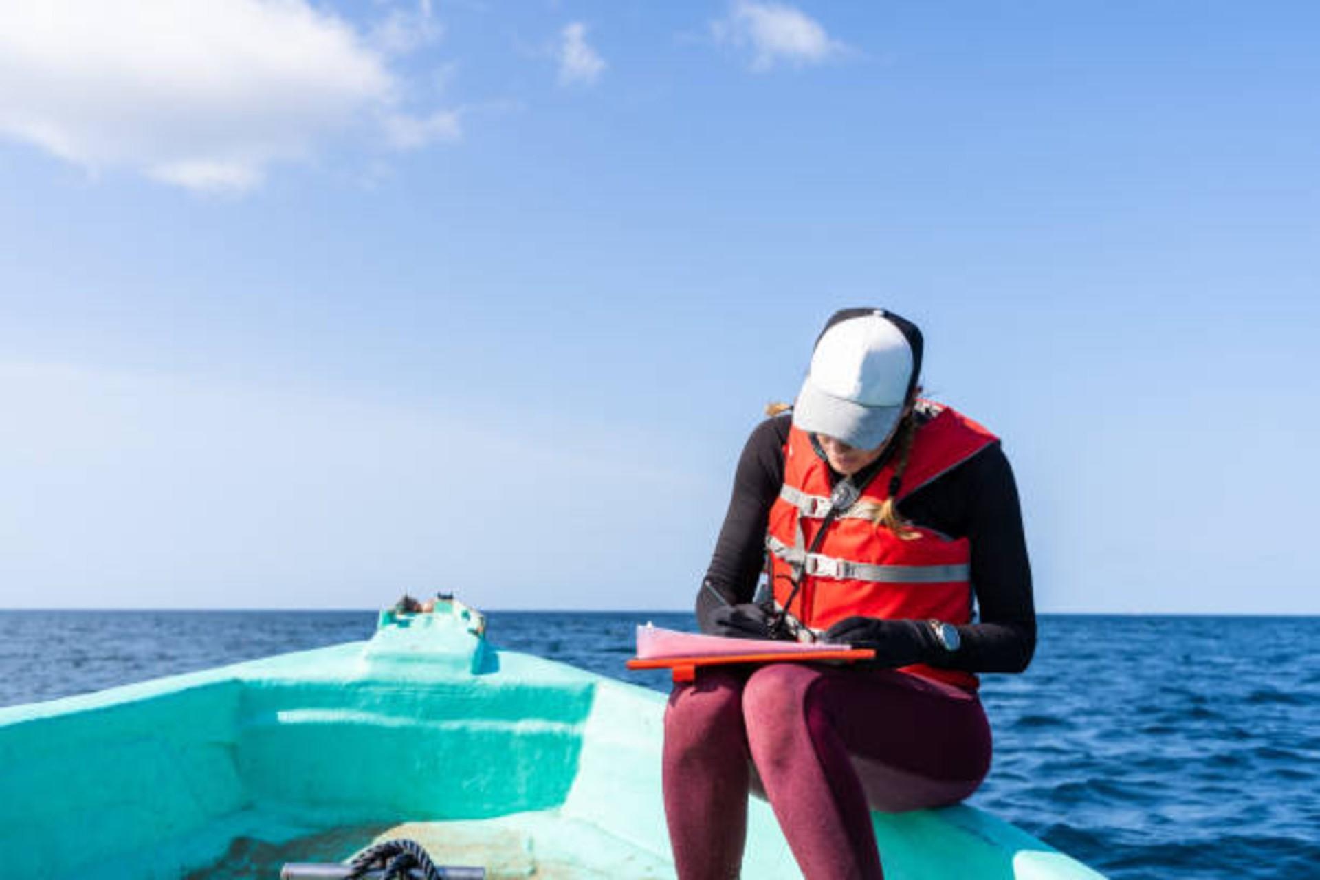 Marine biologist writing down on paper in the boat.