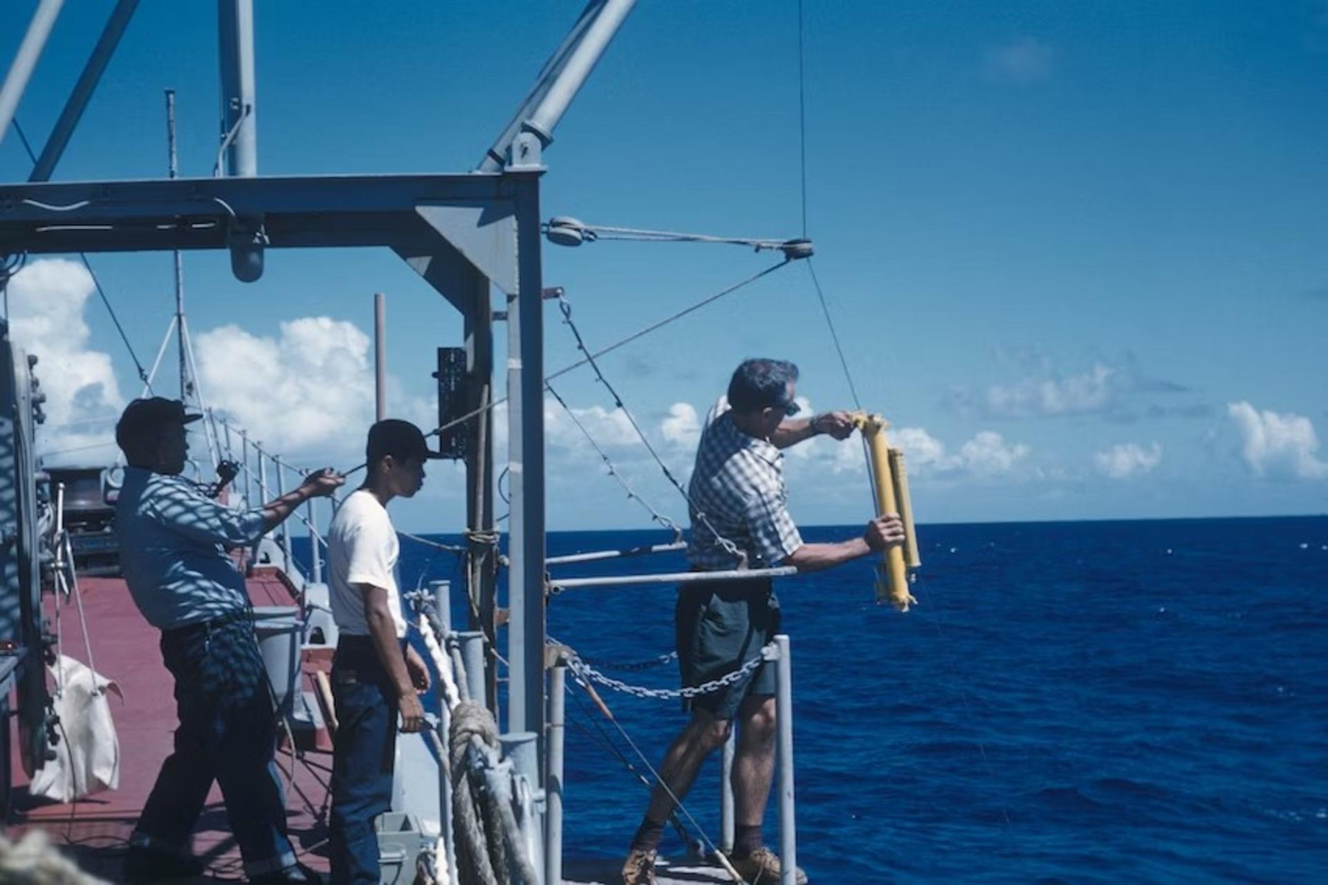 Marine biologists standing on the top of a ship.