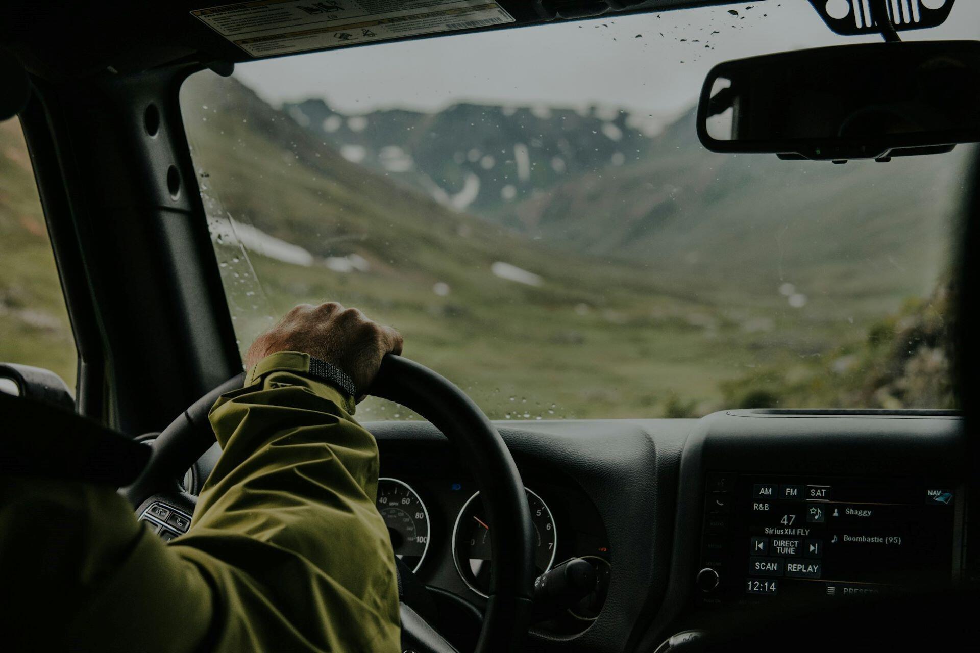 A person driving a car in the mountains.