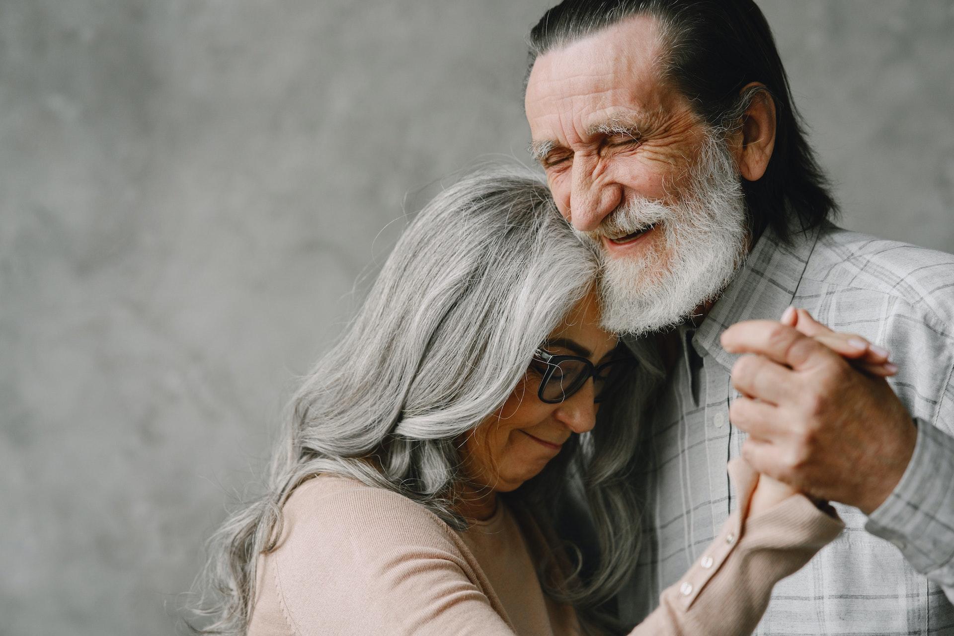 Elderly couple lovingly dancing together and smiling.