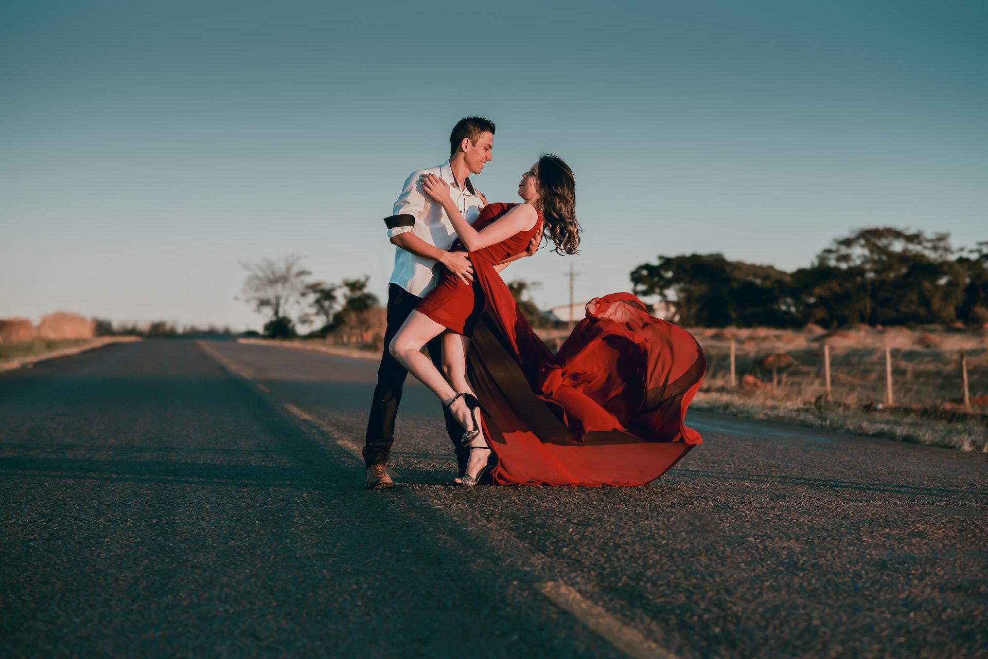 A couple ballroom dancing in formal clothes in the road.