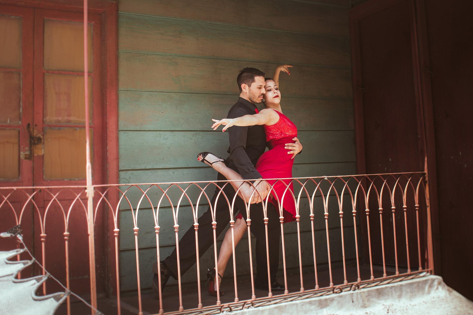 A couple on a balcony dancing where the man lifts the woman.