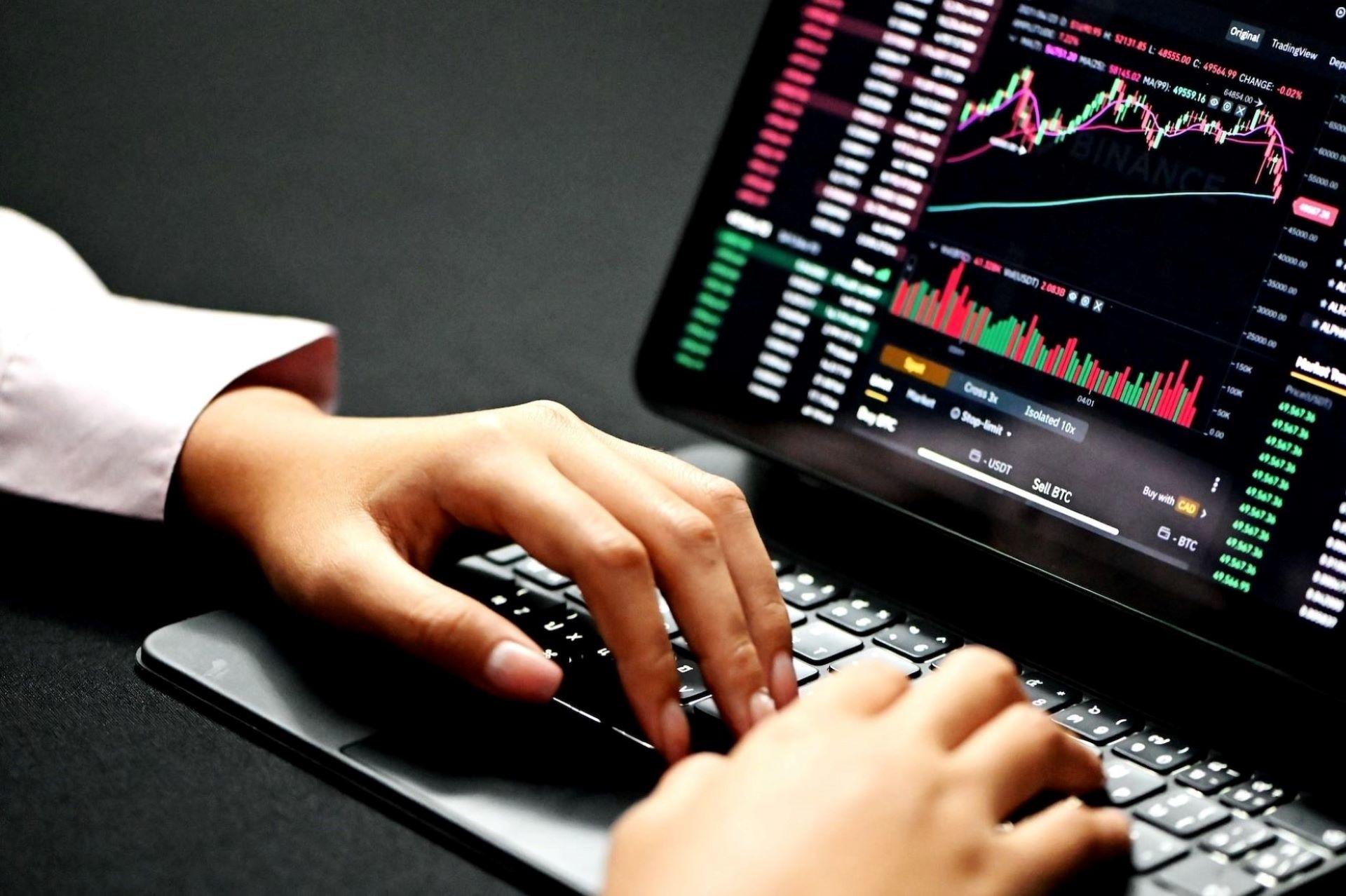 A person trading stocks and crypto on a laptop.