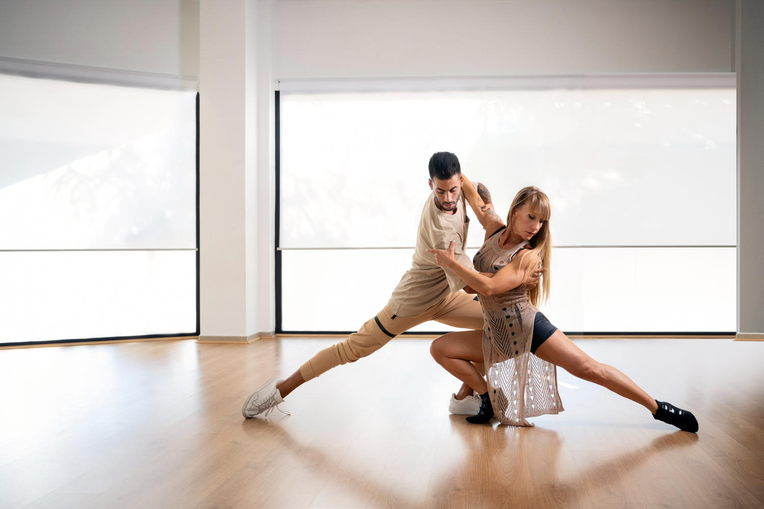 A couple in modern clothes dancing in a large, bright room.