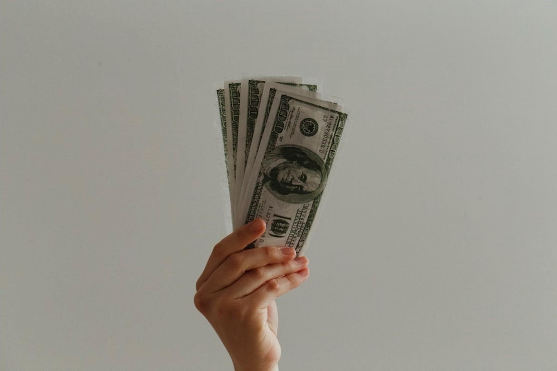 A person with 100 US dollar banknotes in hand