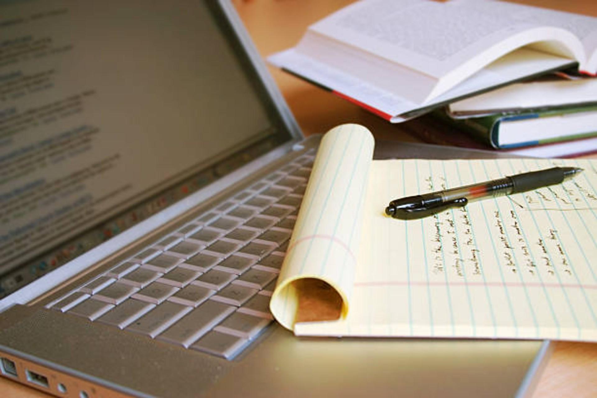 A person writing notes on a book through online classes