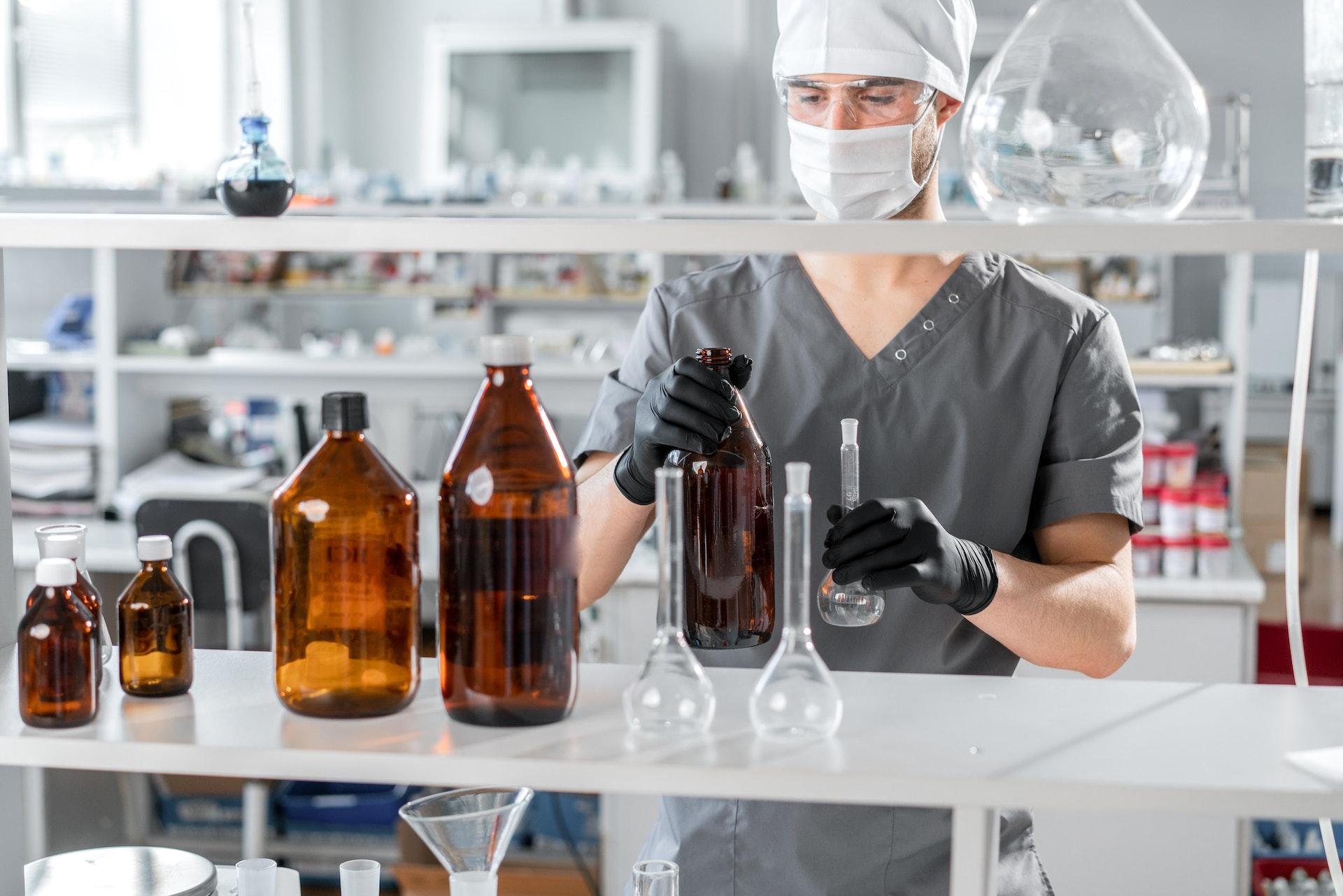 A scientist arranging various bottles on a lab bench.