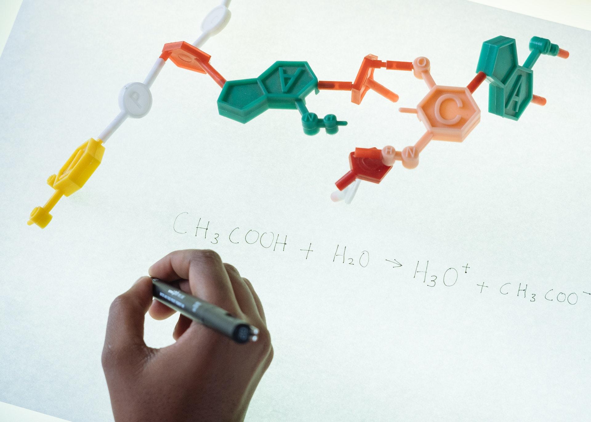 A student writing the chemical composition of a model of a molecule.