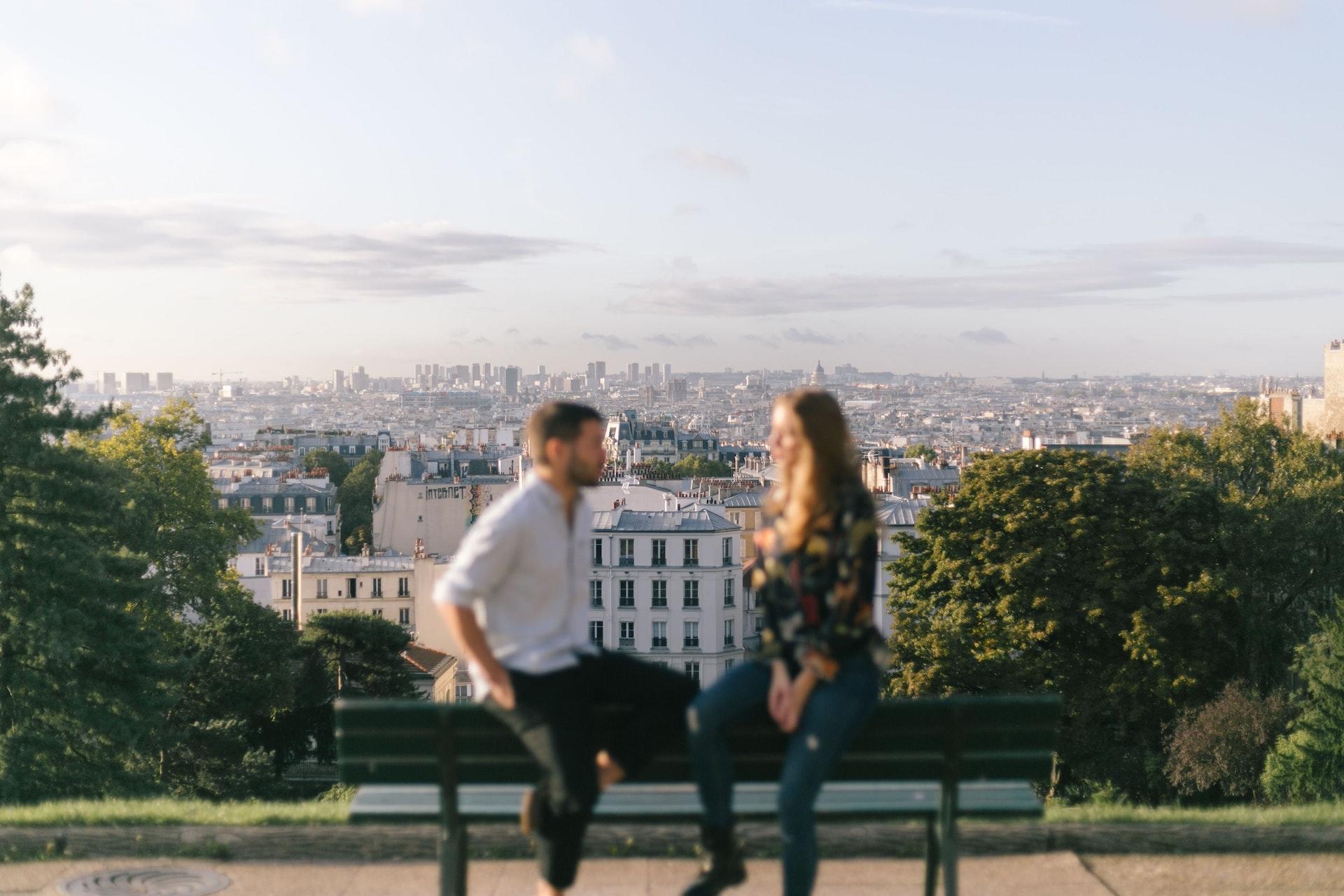 A couple sitting on a bench talking overlooking Paris.